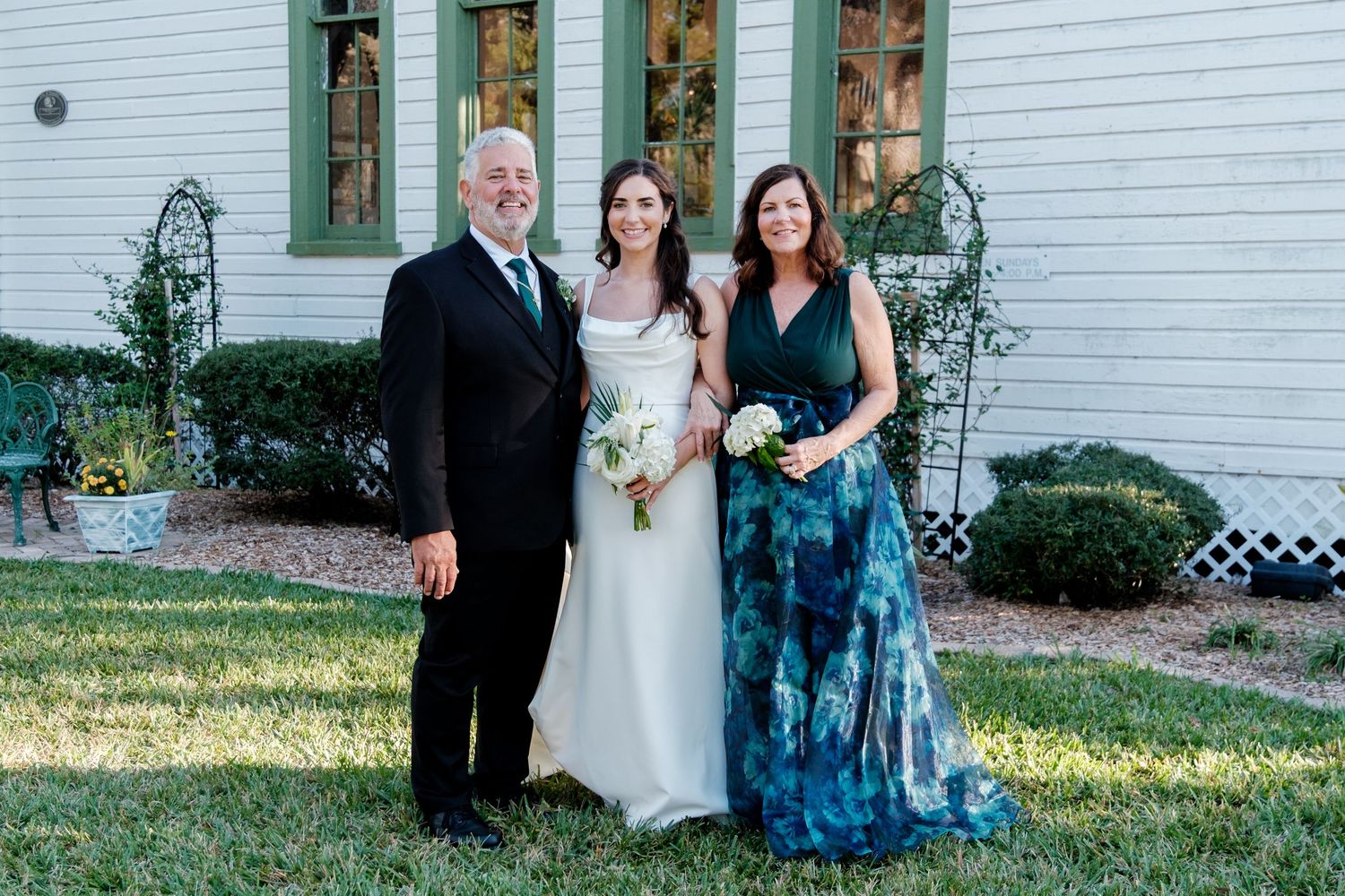 Family wedding portraits taken outside white clapboard building.