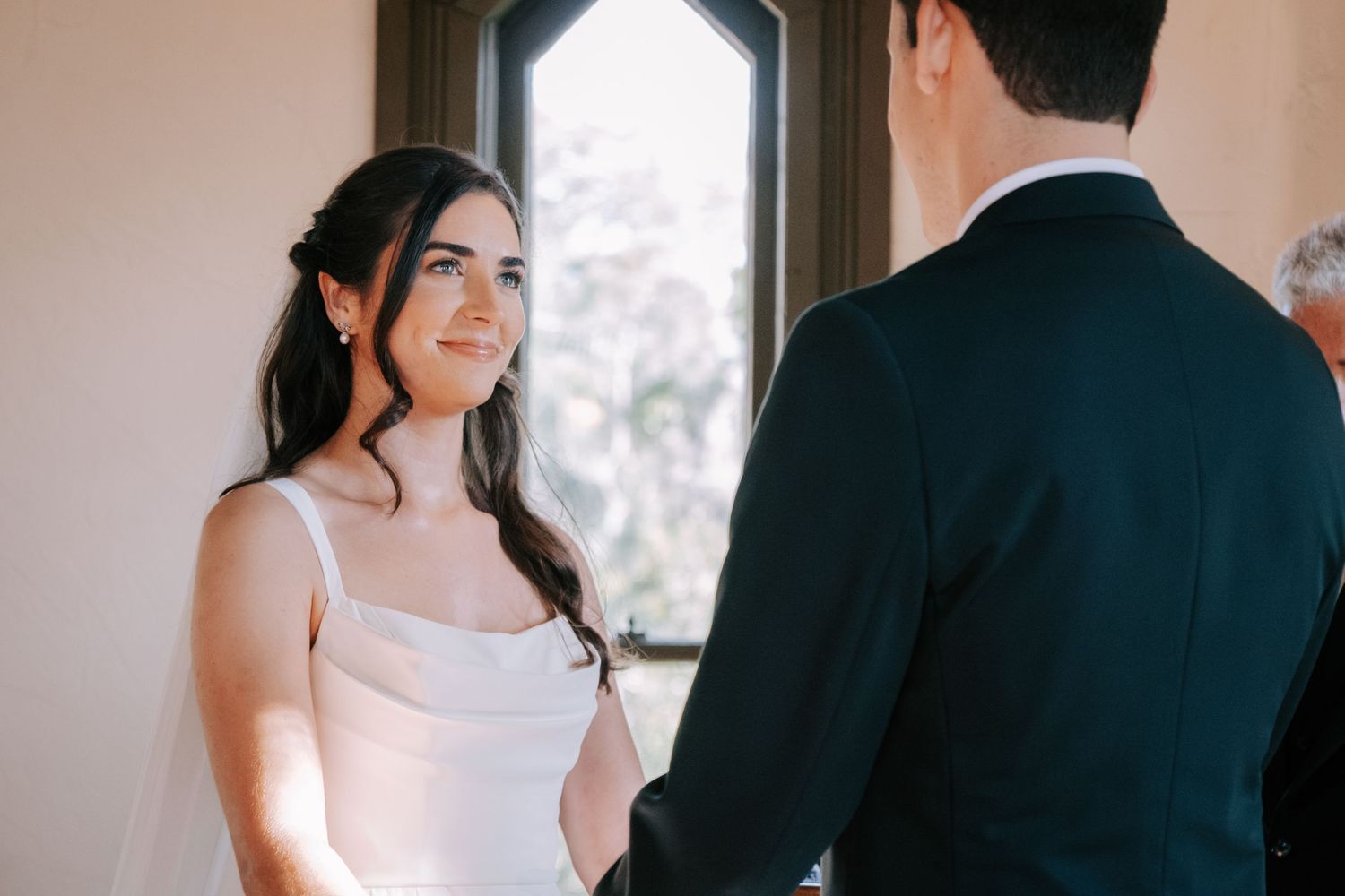 Elegant wedding first look moment in a chapel with gothic windows and natural light.
