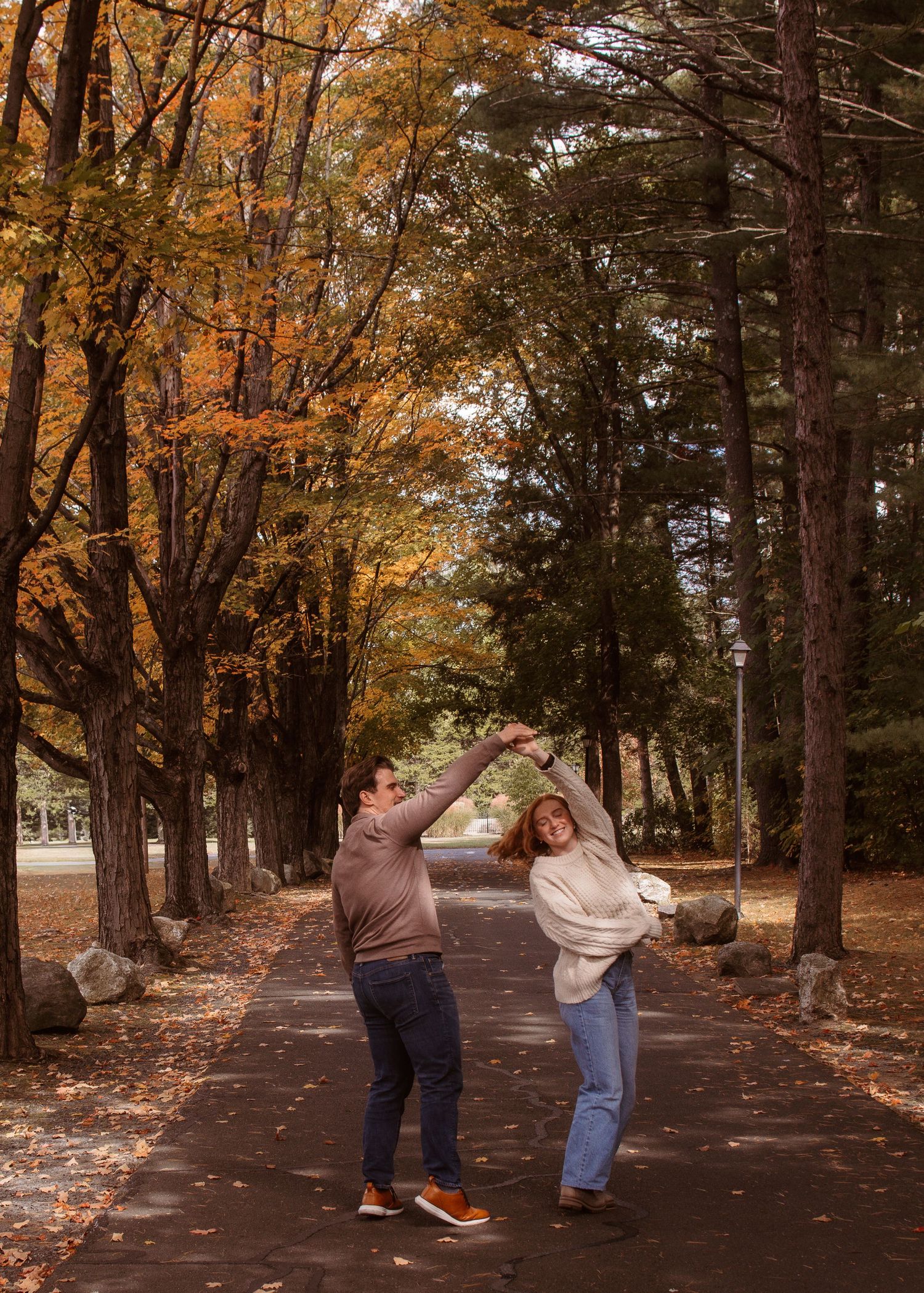 A sequence of photos showing a couple dancing and twirling together on a tree-lined path covered in autumn leaves.