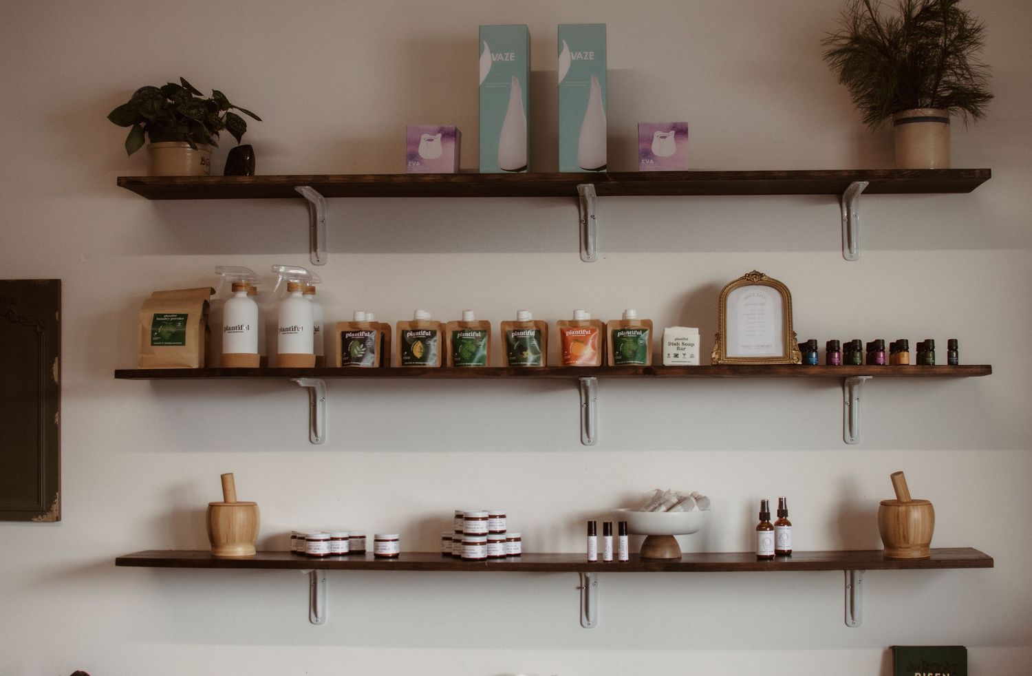 Rustic wooden shelves displaying an eclectic collection of bottles, plants, and decor items in a cozy interior space.