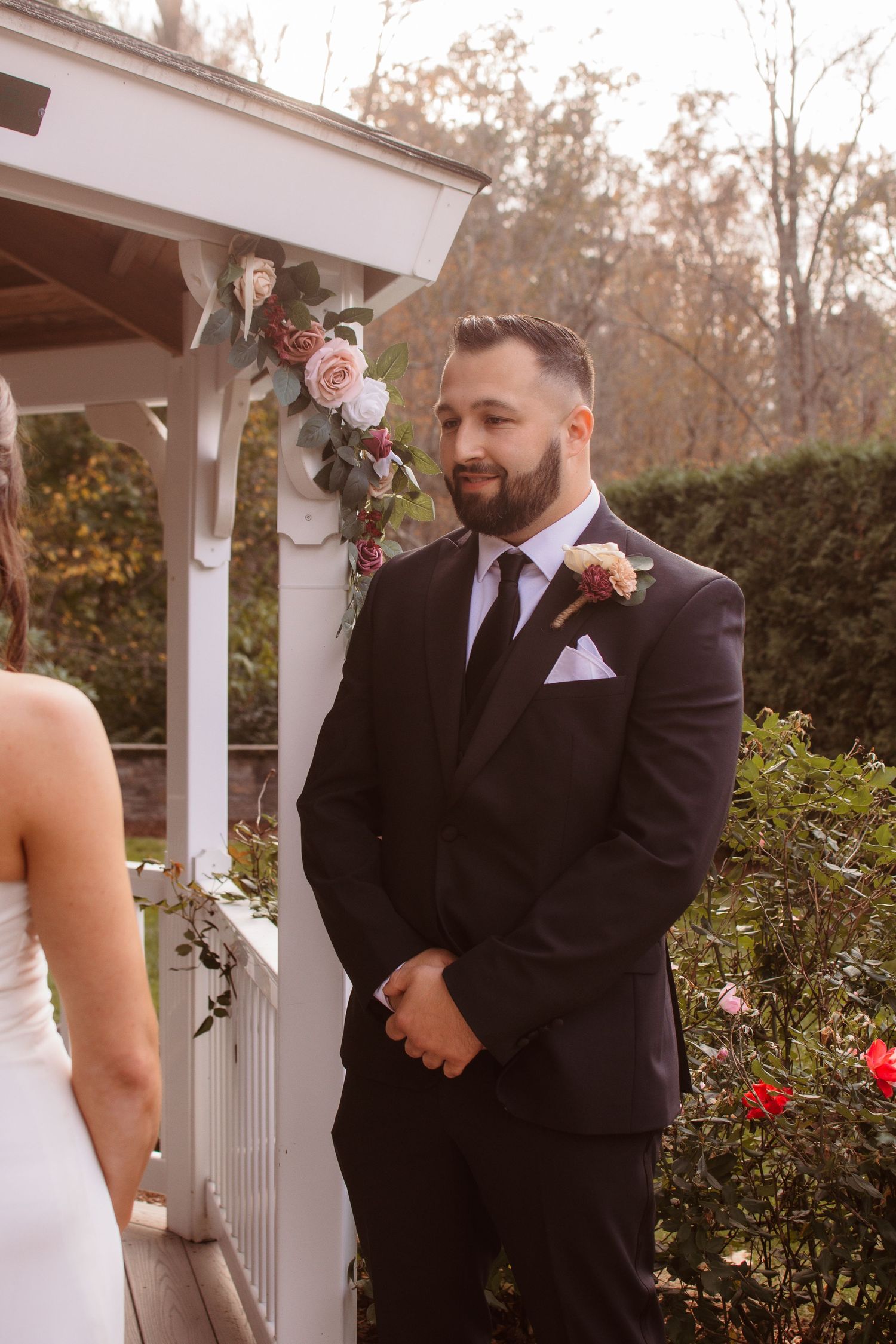 A couple shares an emotional first look moment during their wedding ceremony in front of a white gazebo.