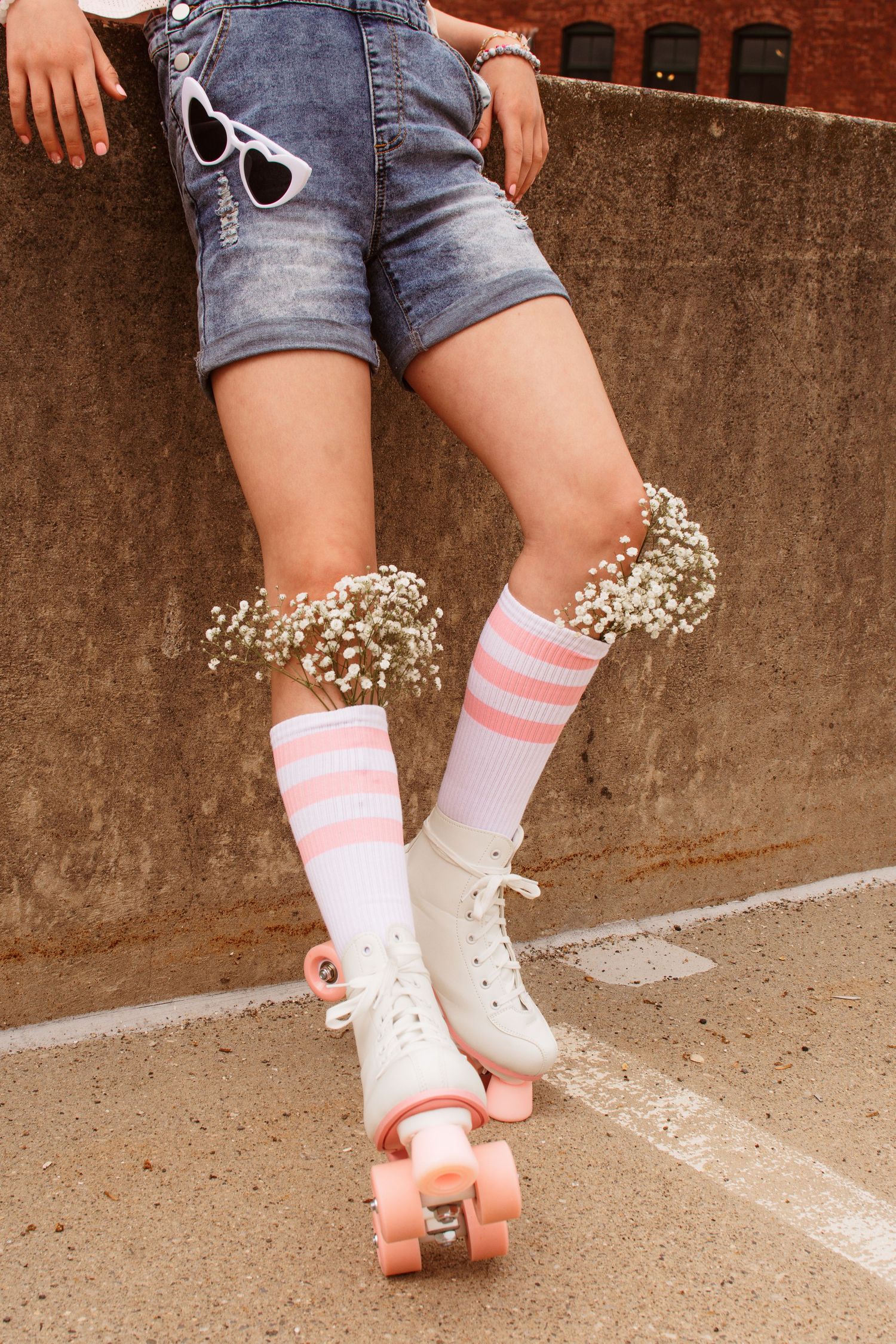 A series of retro-style roller skates with pink striped socks against a brick wall background, creating a vintage aesthetic.