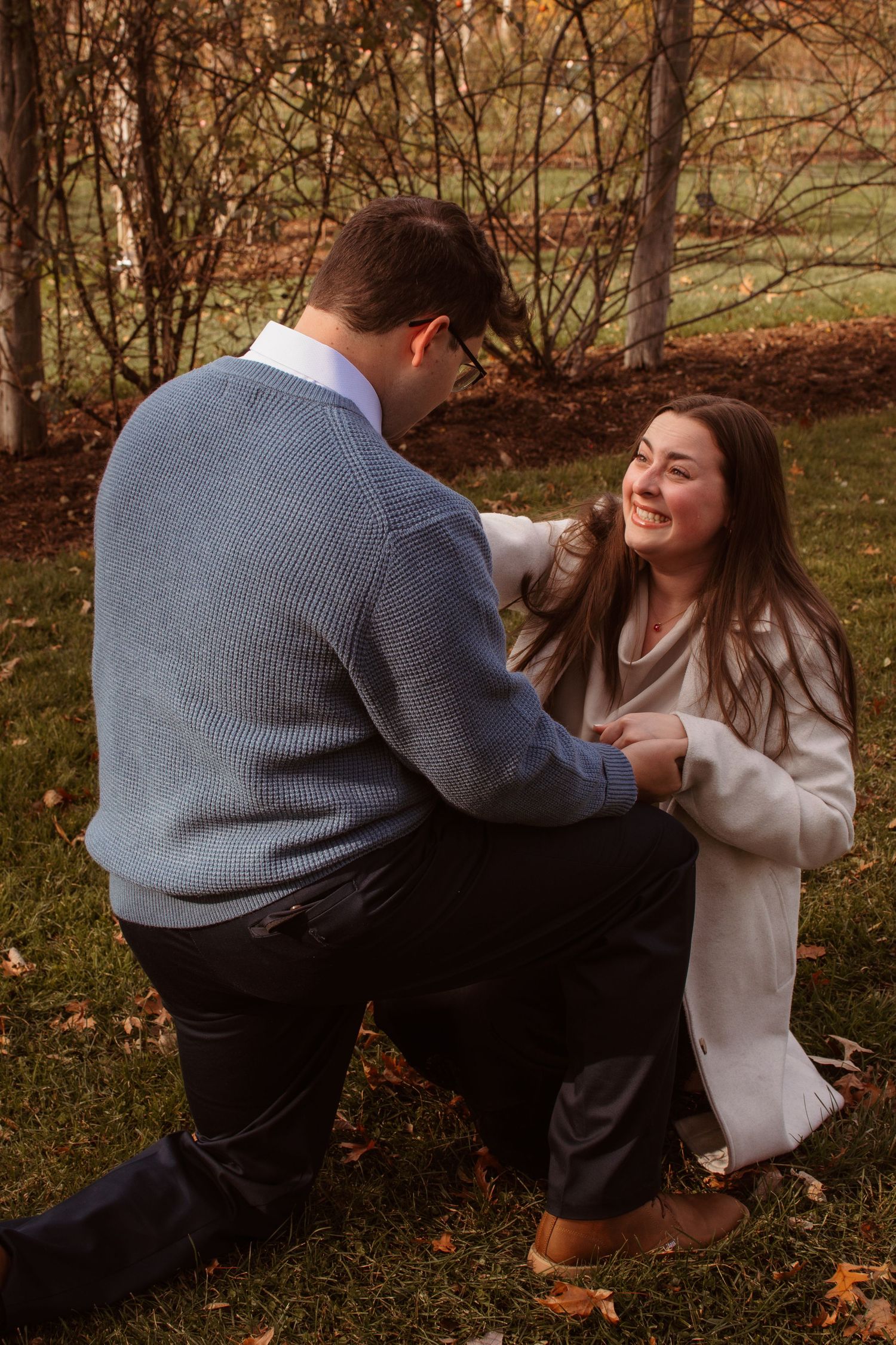 A playful couple in autumn foliage having fun with a sweater in a series of candid outdoor photos.