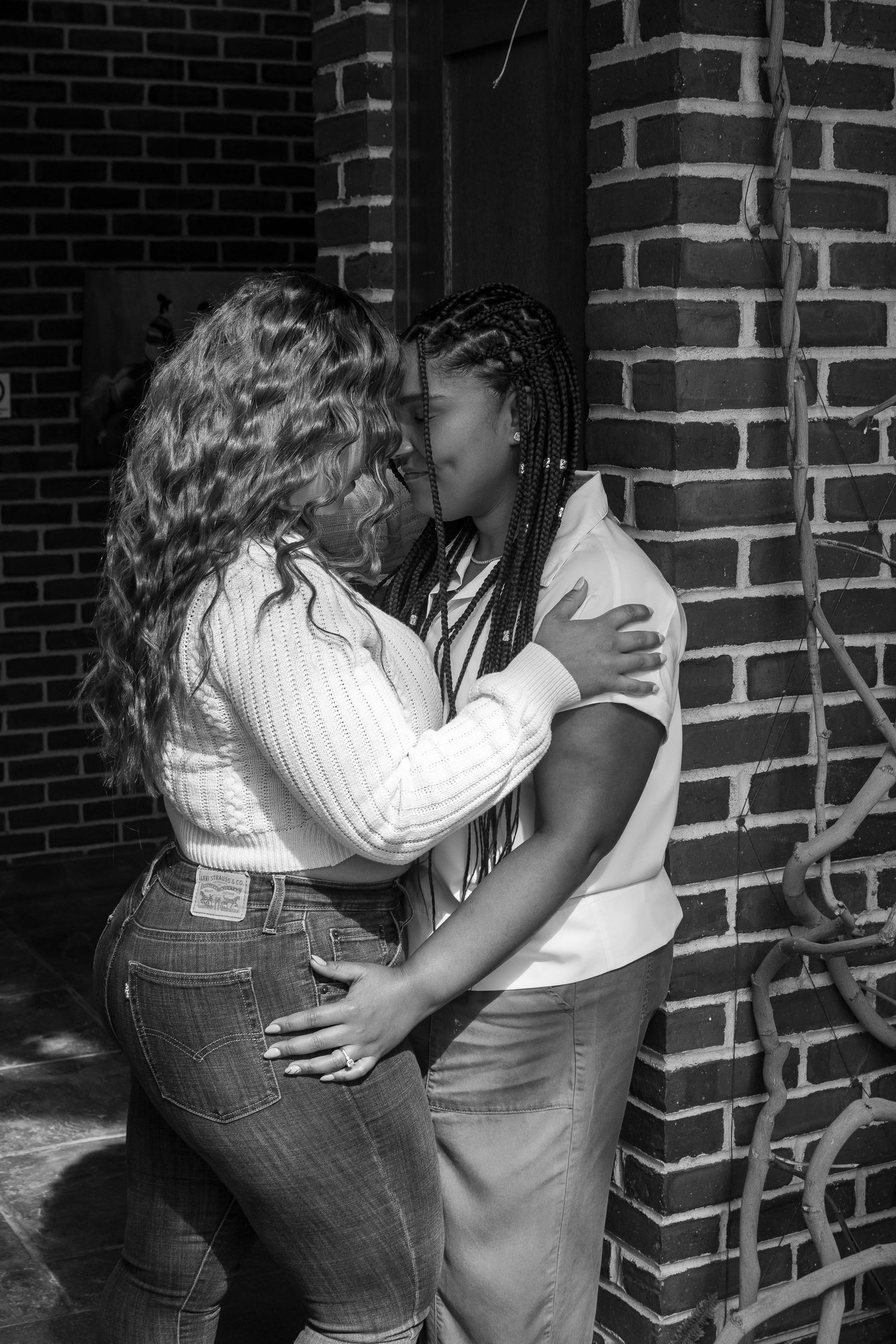 A sequence of black and white photos showing two people embracing against a brick wall.