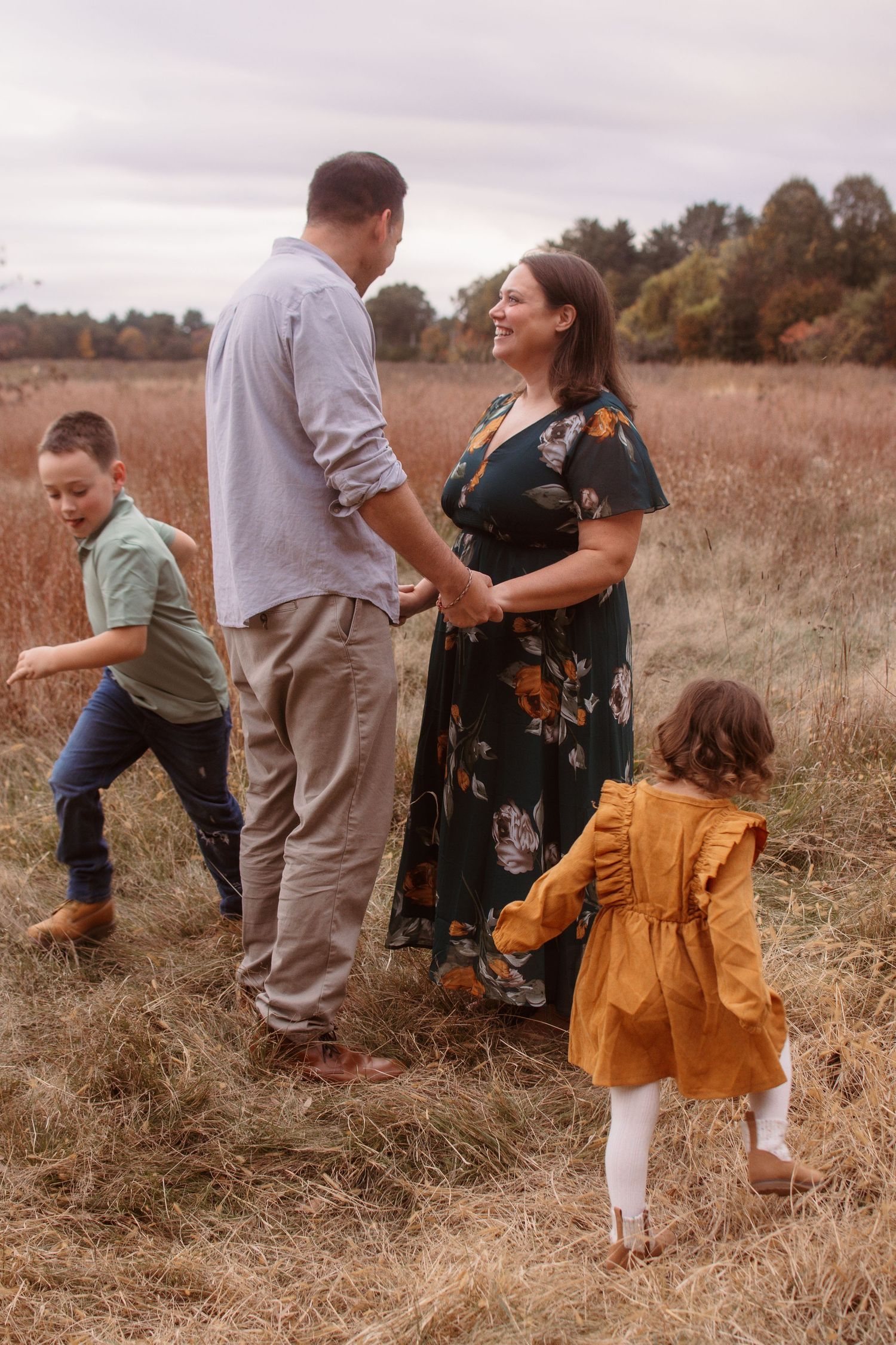 Family enjoying a candid moment together in a golden autumn field during sunset.