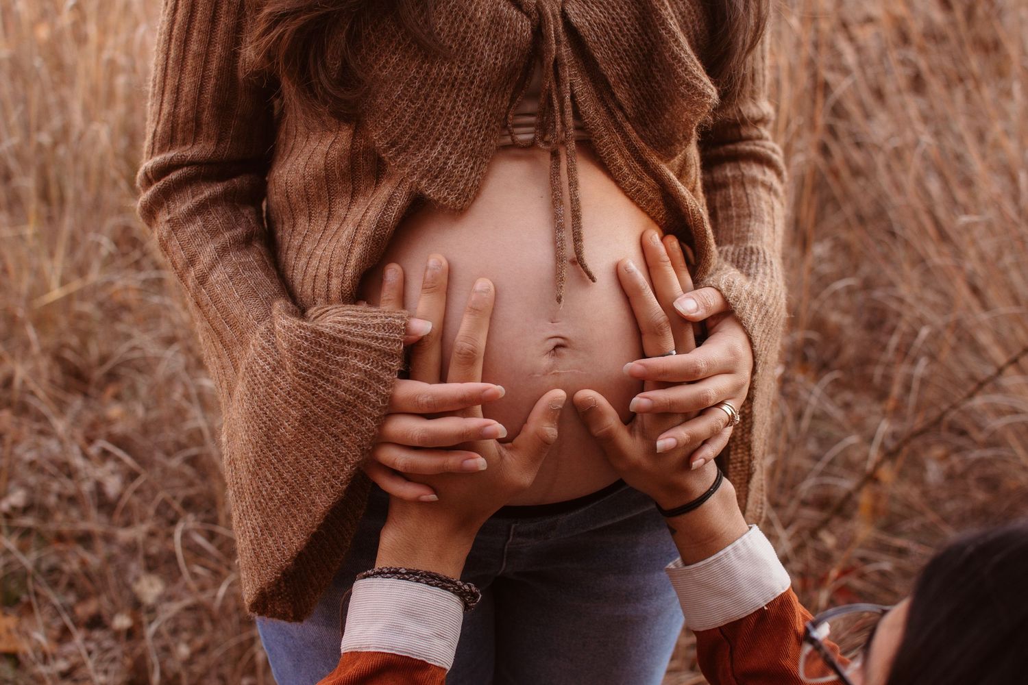 A series of sepia-toned photographs showing hands holding a small baby's feet against a natural outdoor background.