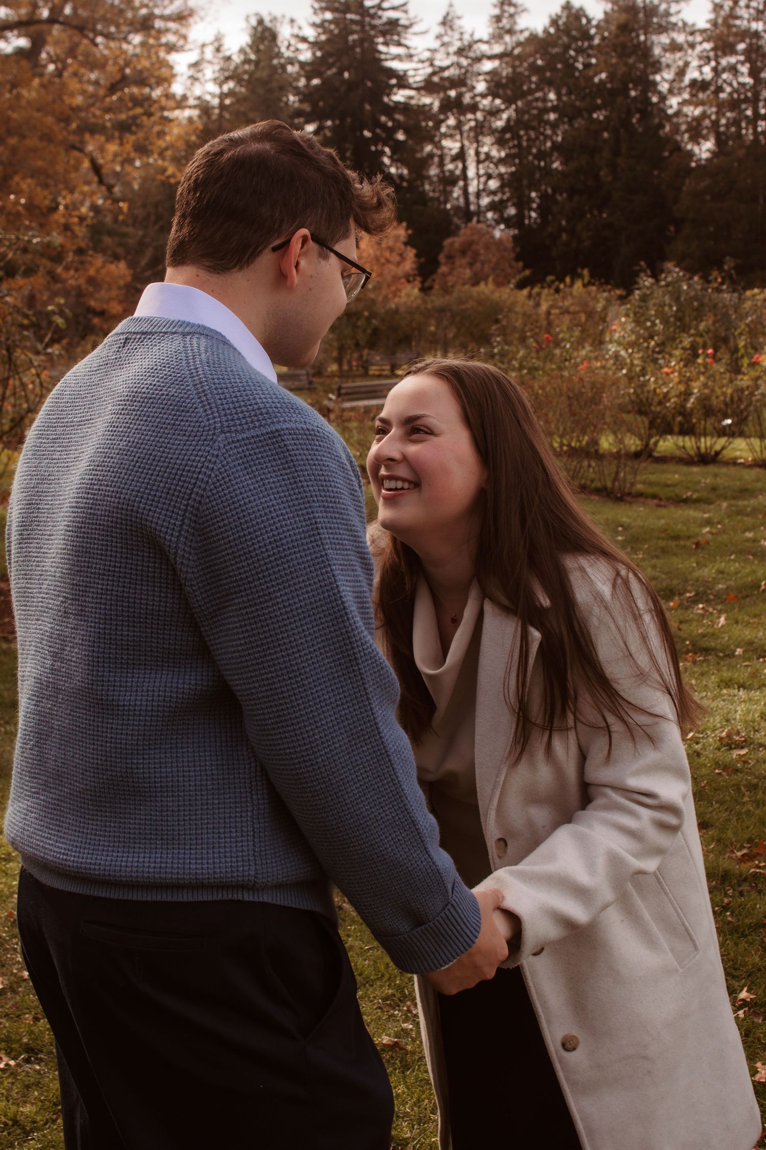 A joyful couple sharing laughter together in a park during golden autumn hours.