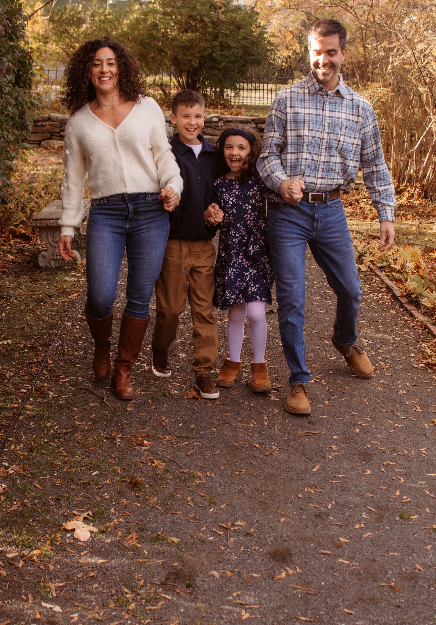 Family walking together in autumn with fallen leaves on a path wearing coordinated brown and blue outfits.