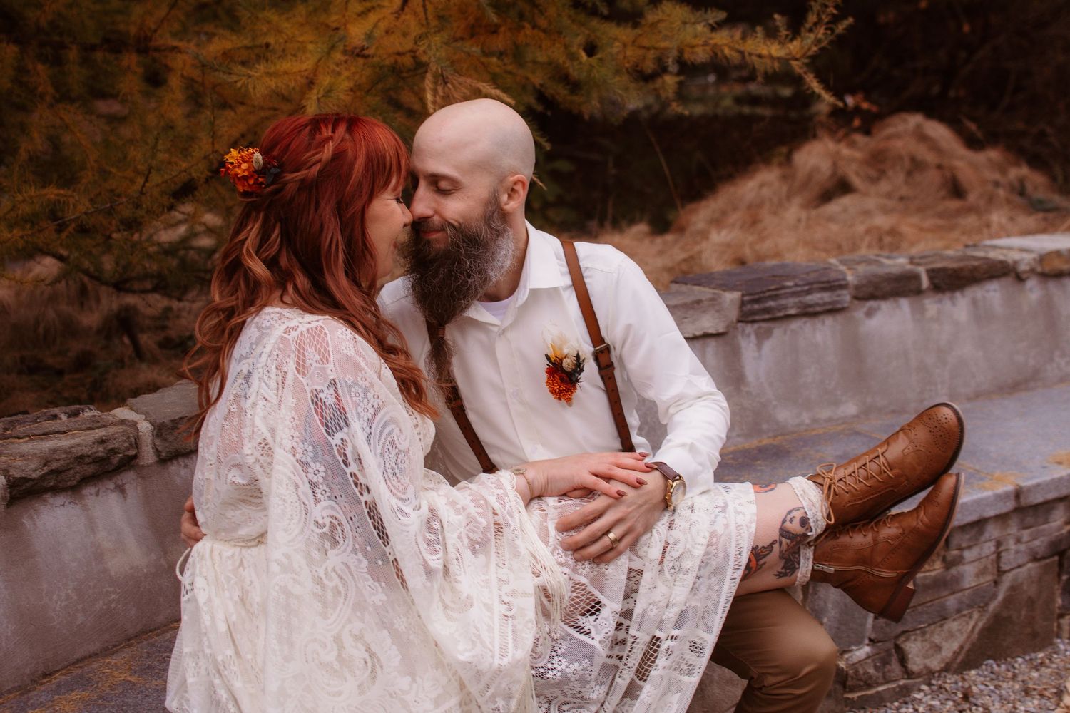 A romantic autumn wedding photo shows a couple embracing on stone steps with the bride wearing a lace dress.