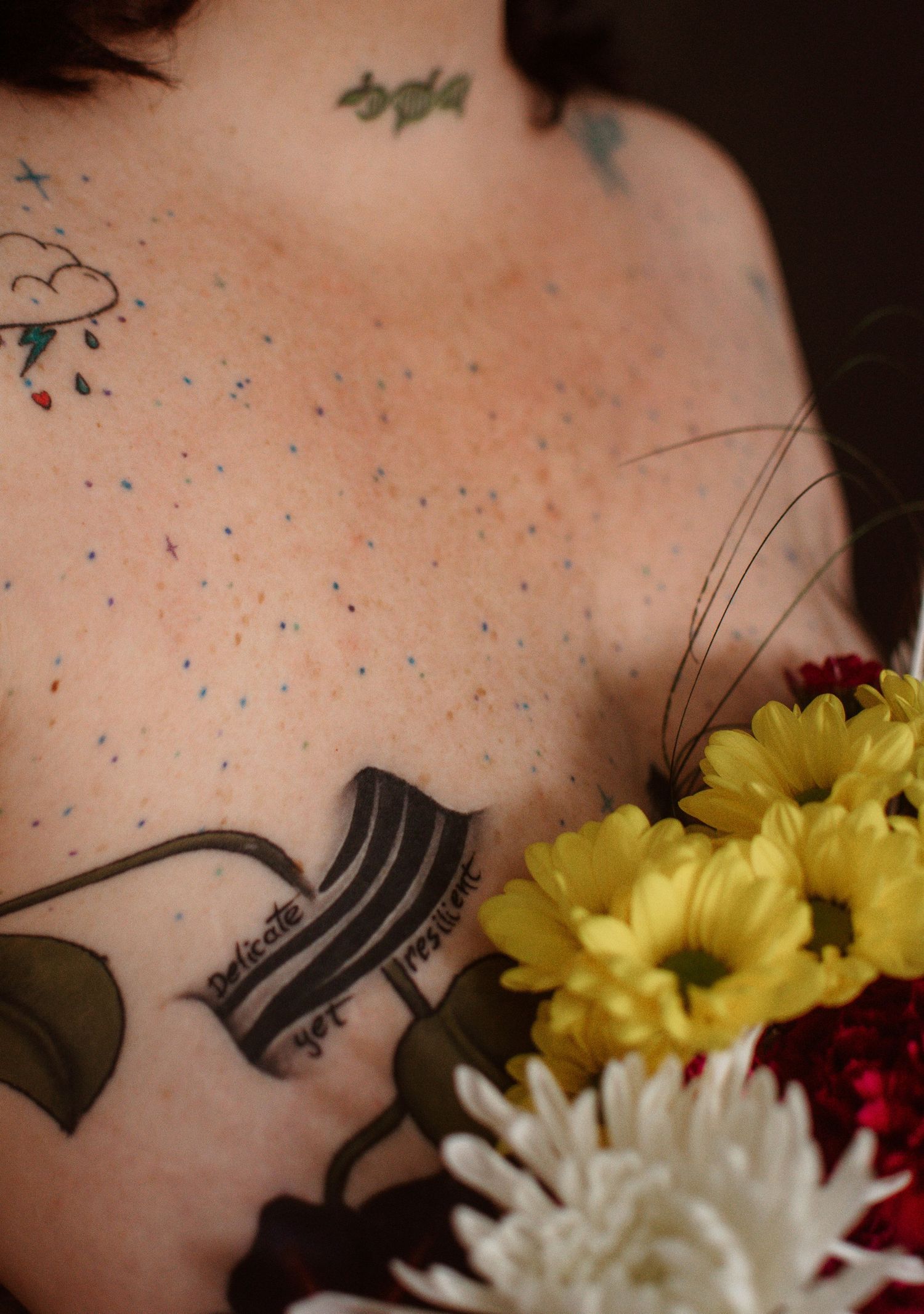Close-up of freckled skin with a tattooed gramophone and bright yellow and white daisies in frame.