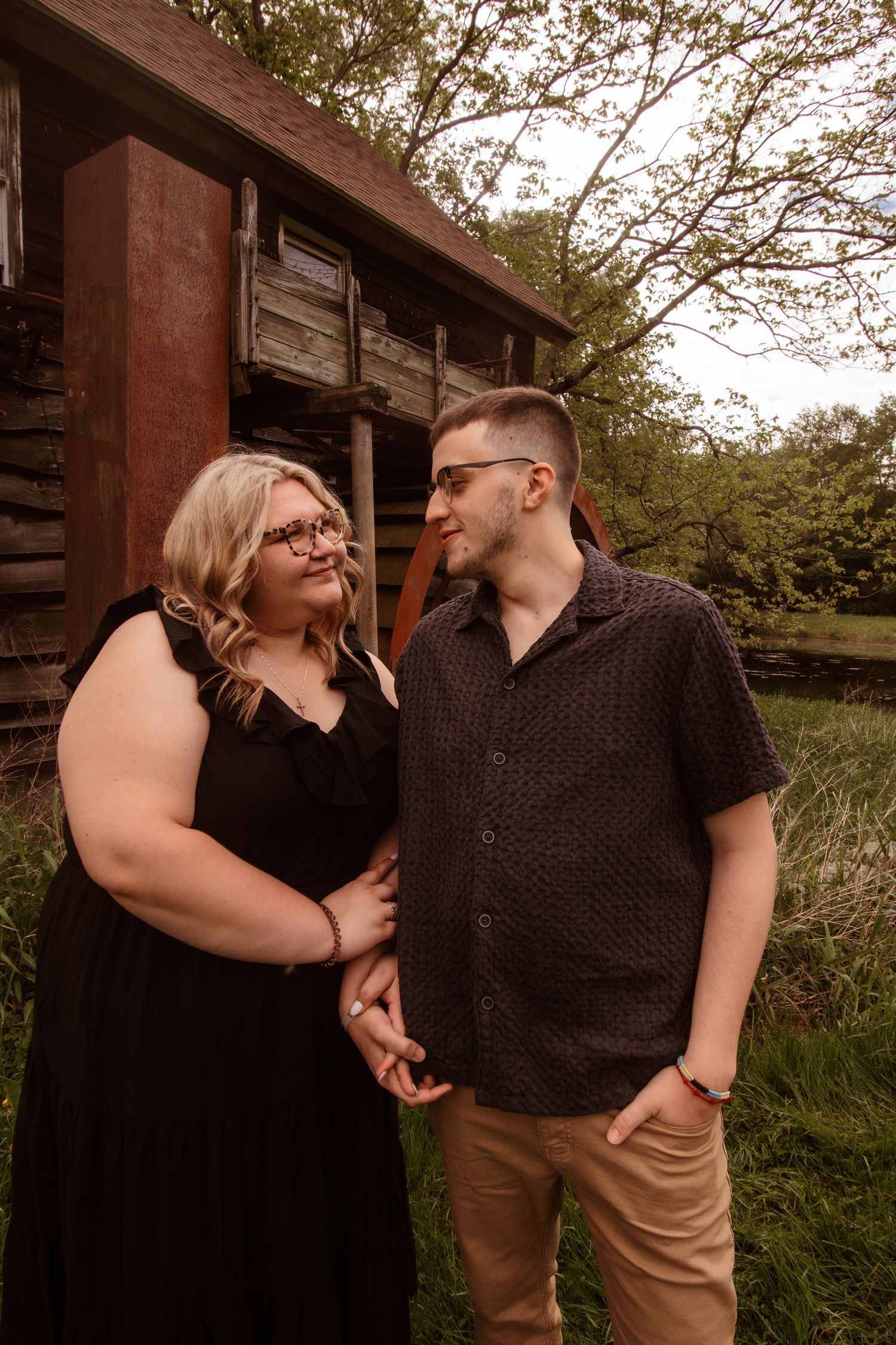 Romantic couple shares loving gaze in front of rustic barn during outdoor photo session at golden hour.