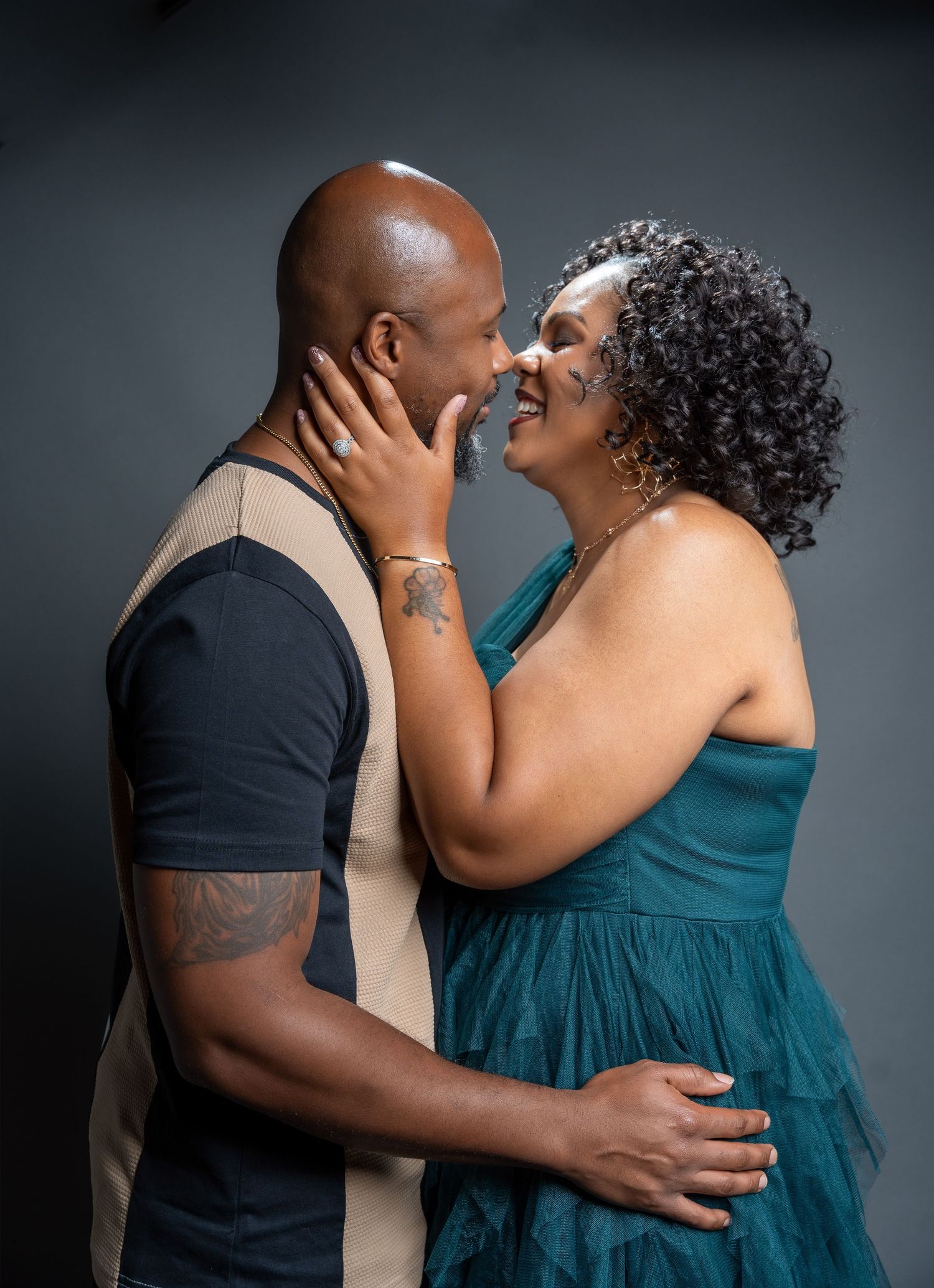 A romantic studio portrait captures an intimate moment between a couple in formal attire.