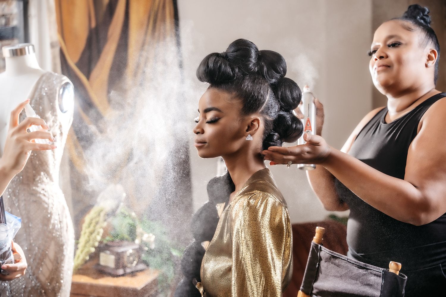 A beauty styling session with hairspray creating a misty effect in natural window light.