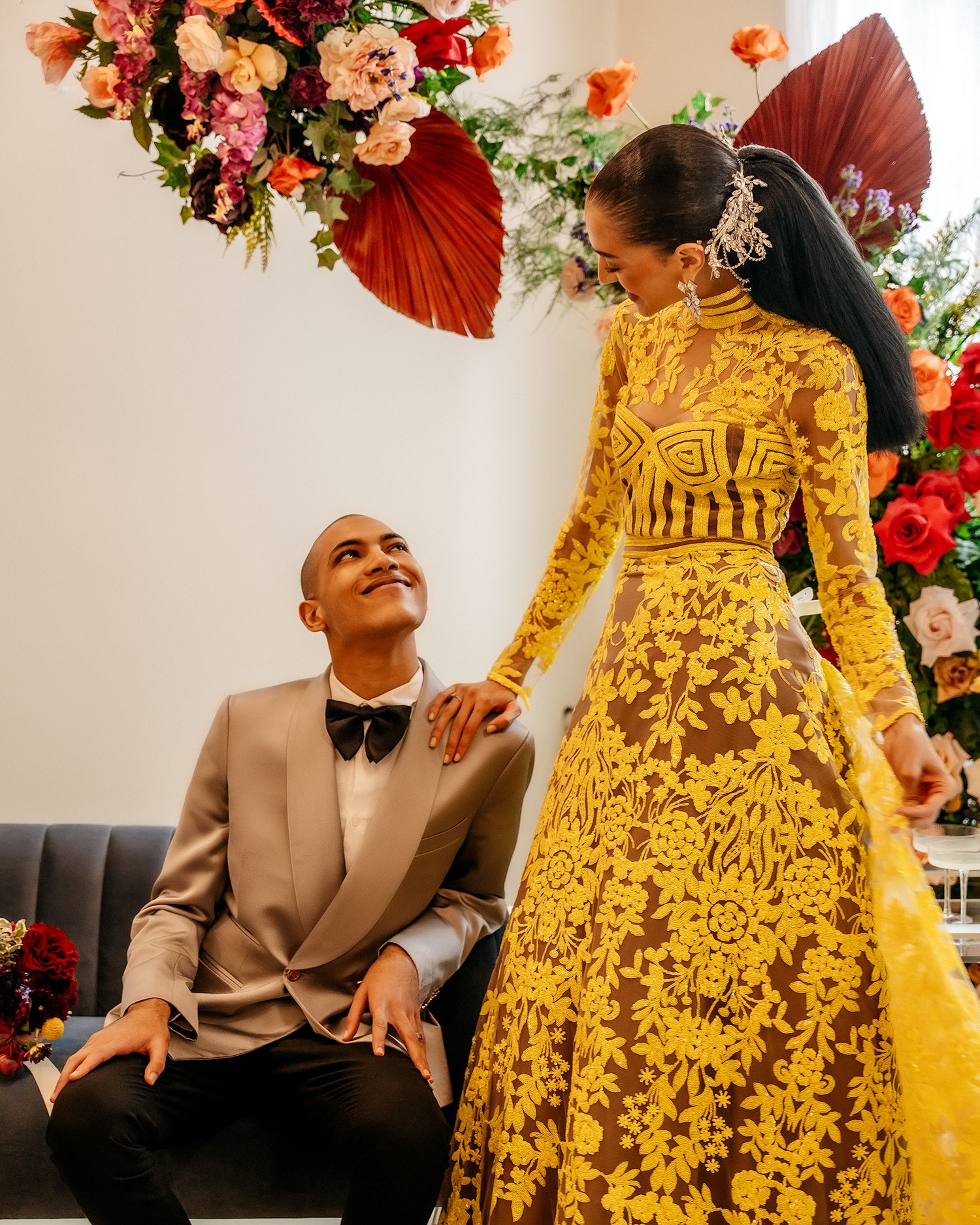Intimate moment captured with couple in yellow gown and beige suit surrounded by florals.