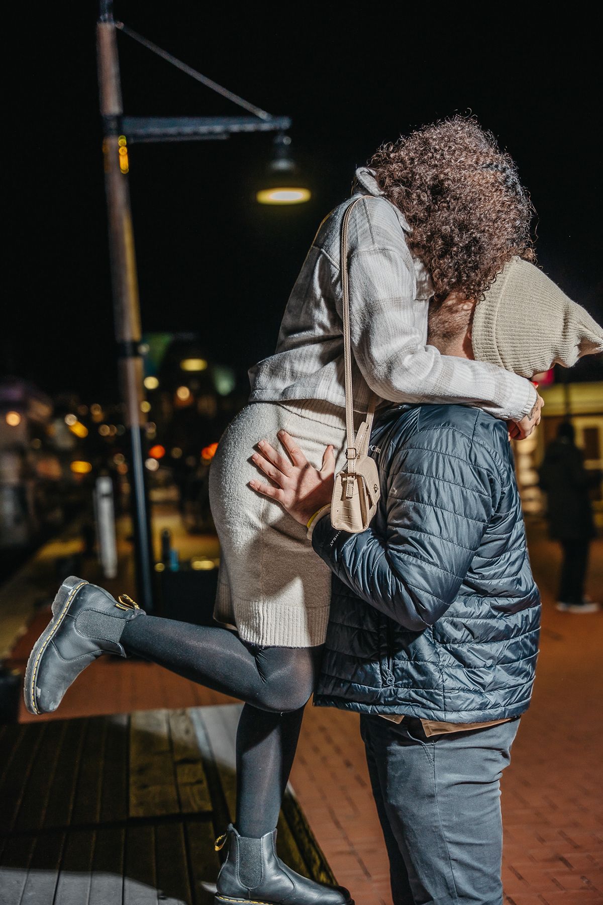 A romantic nighttime embrace under a street lamp showing a couple sharing an intimate moment.