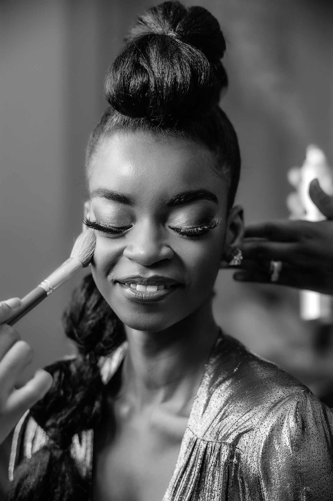 Black and white beauty photo showing makeup application in dramatic lighting.