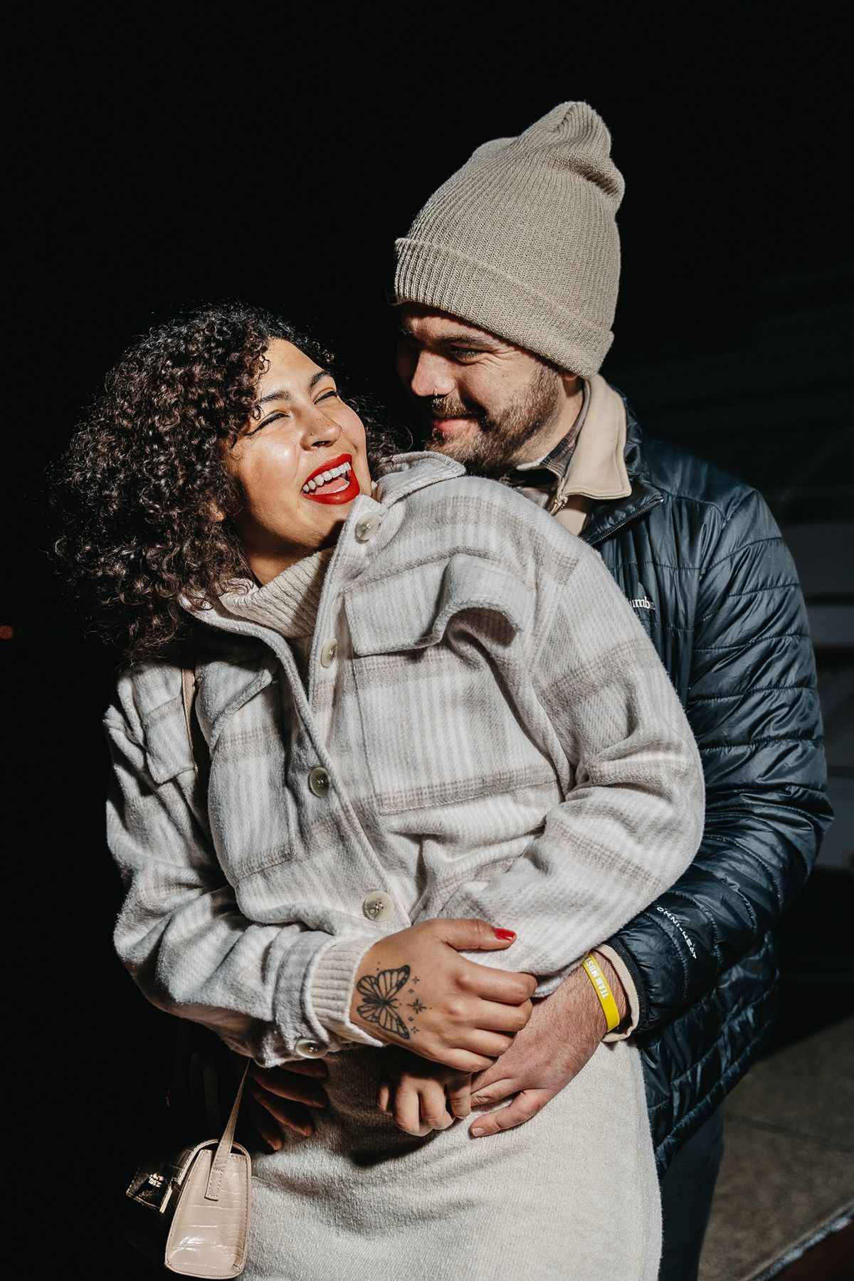 Couple in winter coats sharing an intimate moment outdoors at night.