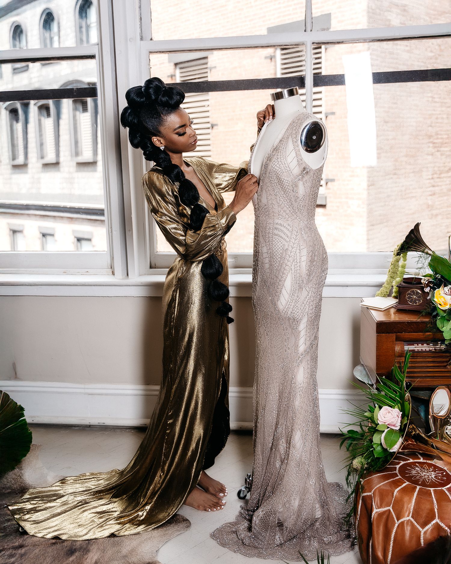 Gold metallic gown and silver dress form showcased in studio setting with floral decor.