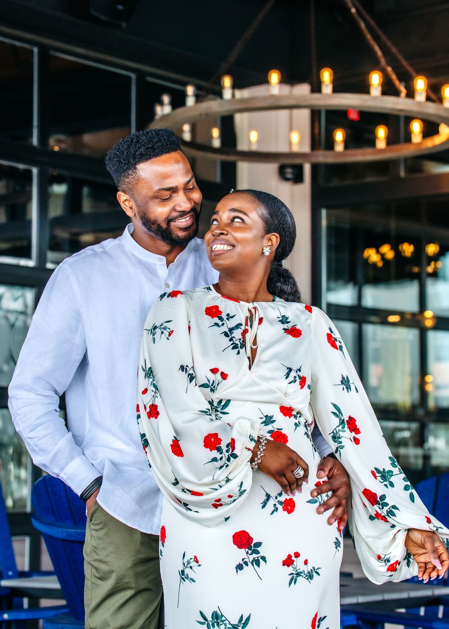 A couple shares a joyful moment together in a restaurant with warm lighting and floral printed attire.
