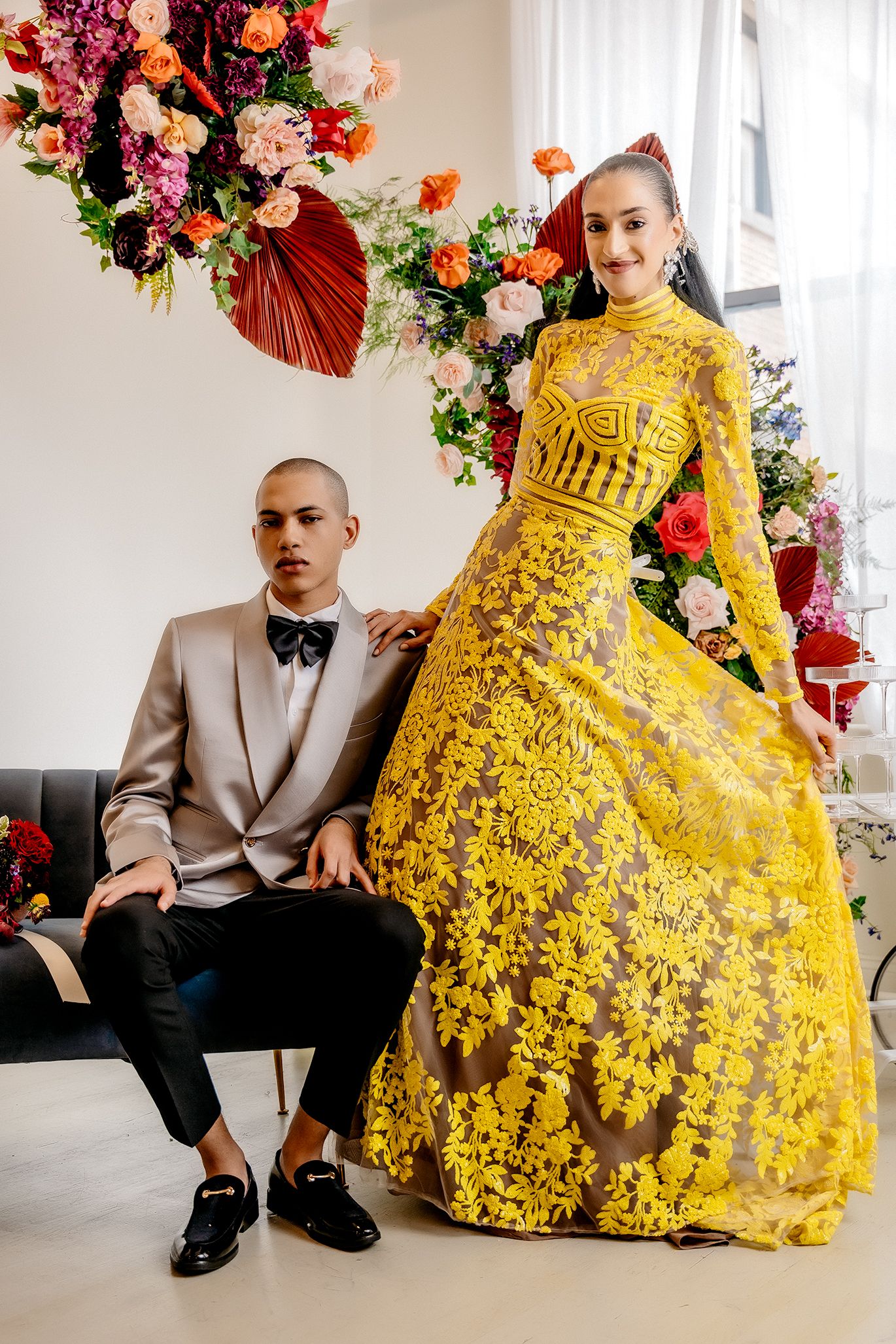 Elegant couple photographed with vibrant floral arrangements and burgundy palm fan decorations.