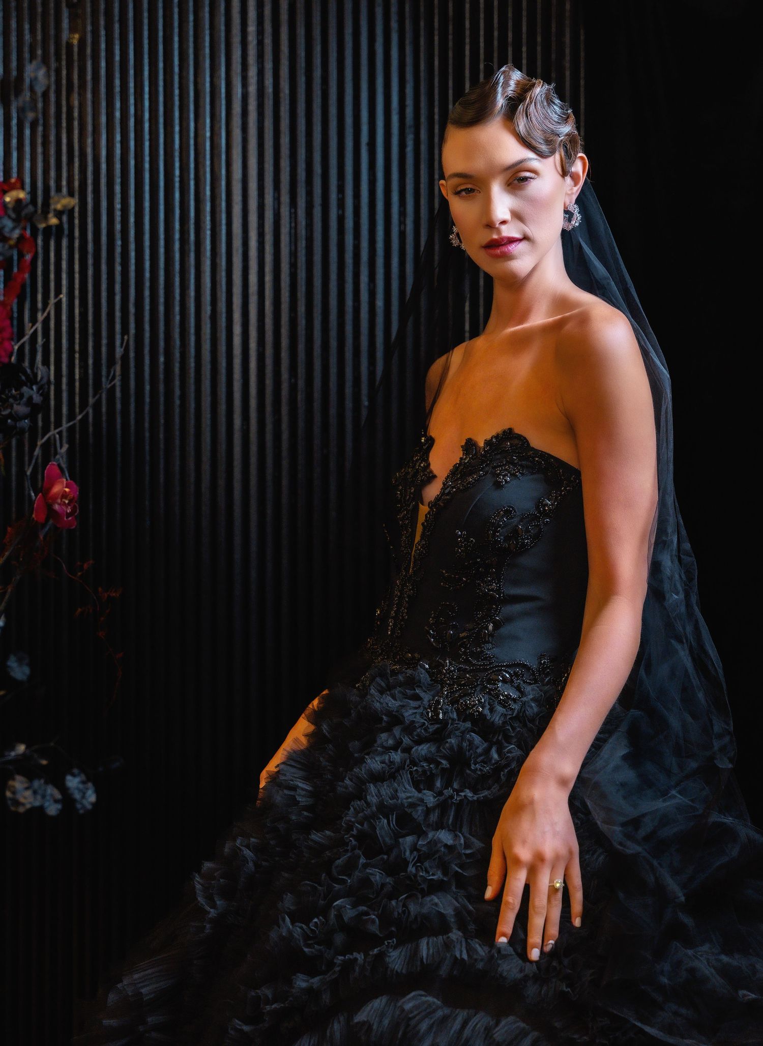 Dramatic black bridal gown with strapless neckline and lace details against dark background.
