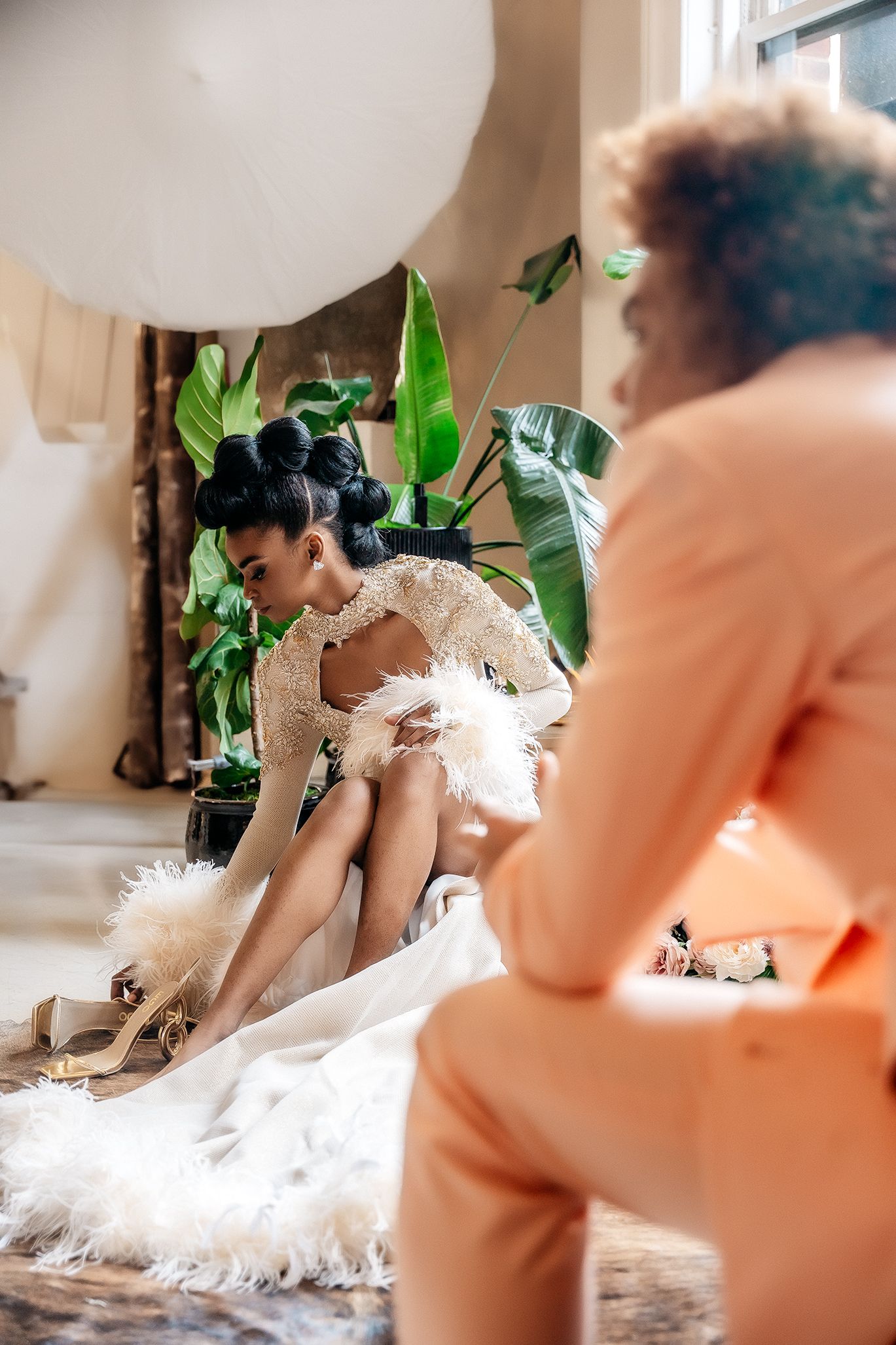 Fashion editorial with white feather dress and large balloon amid tropical greenery.