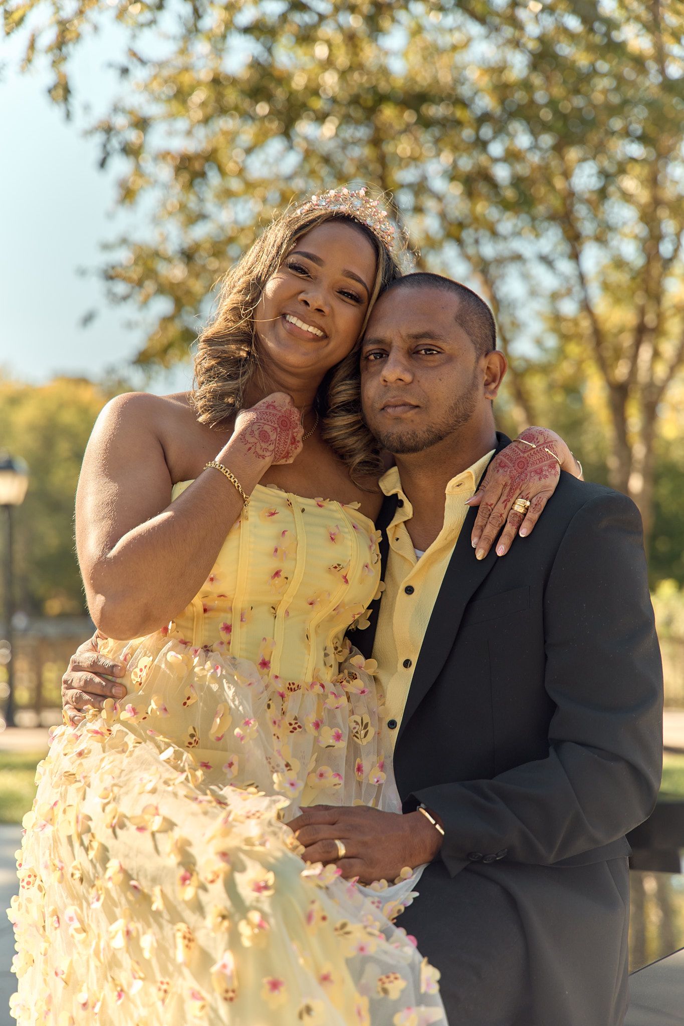 A joyful couple poses outdoors in formal attire during golden hour.