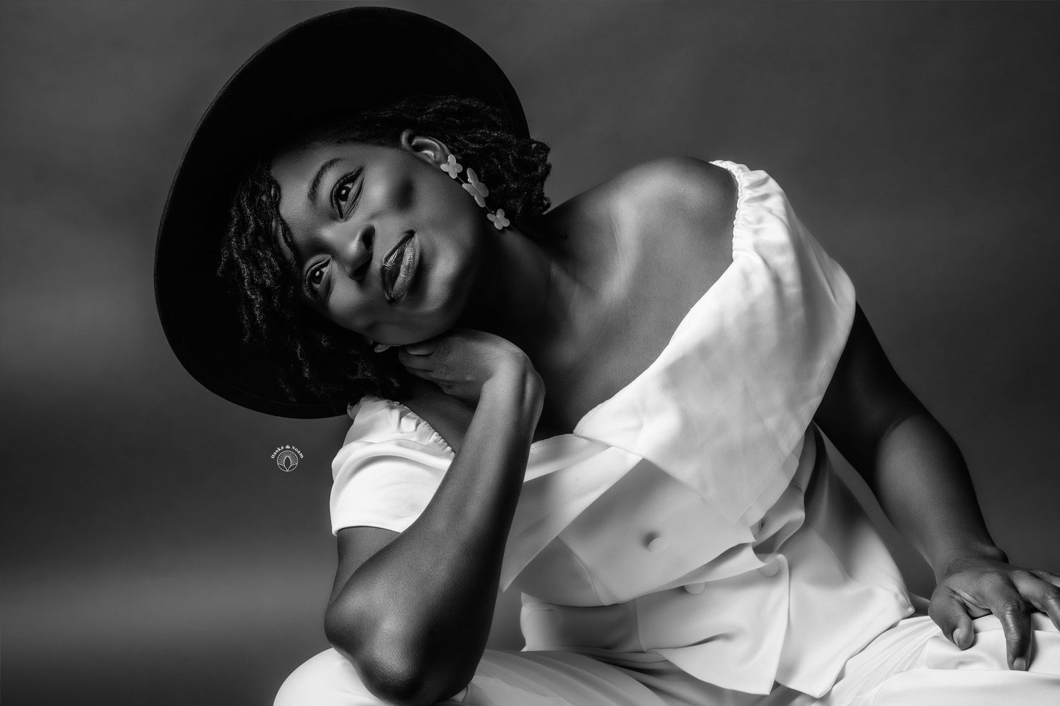 Artistic black and white portrait of a person in white clothing with a dramatic pose.