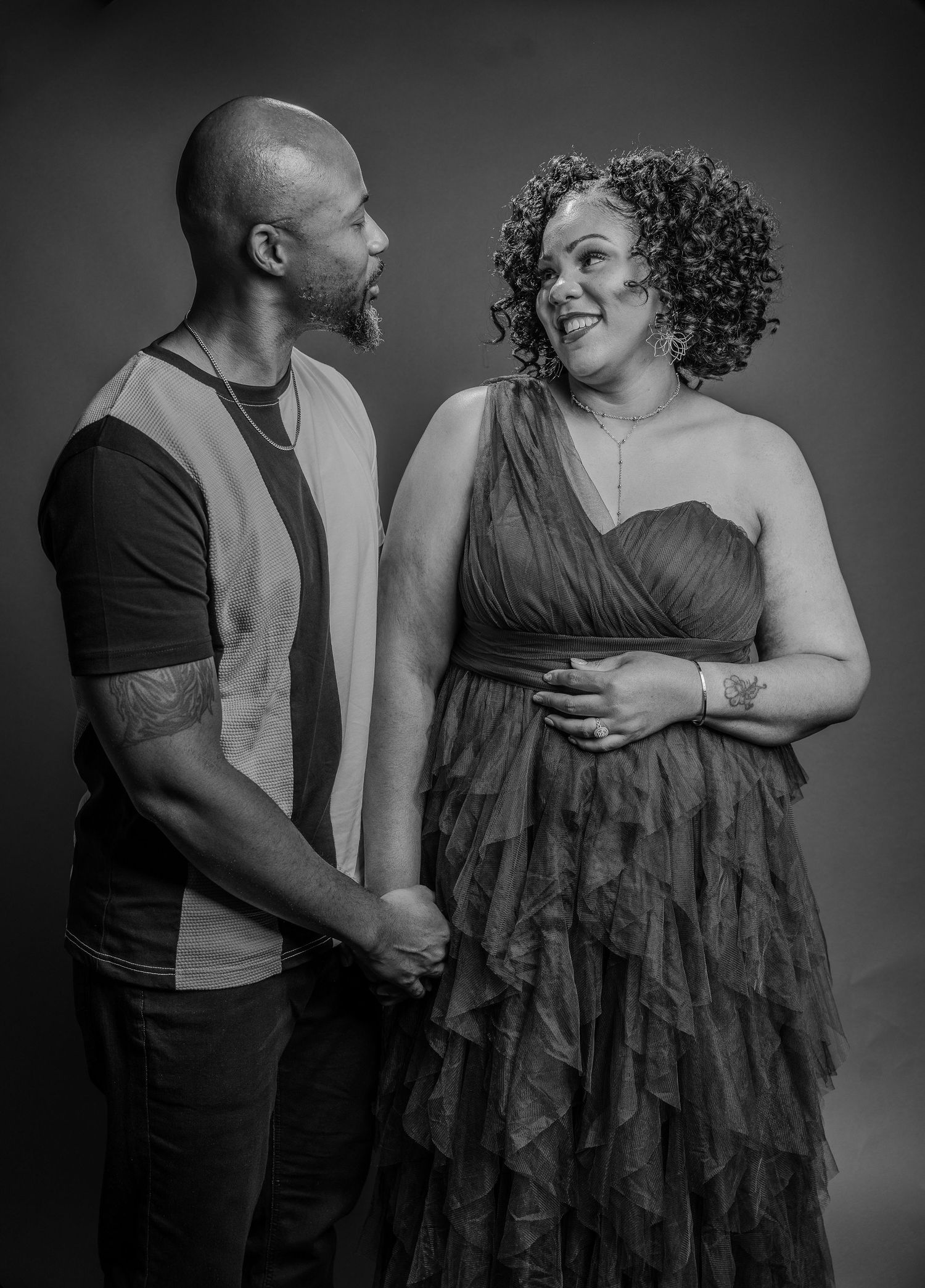 A black and white portrait of a couple sharing an intimate moment in formal attire.