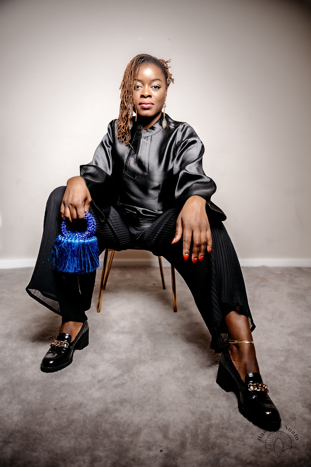 Fashion portrait showing black satin outfit with blue handbag accessory.