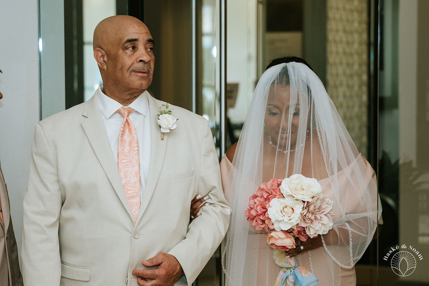 A touching moment during a wedding ceremony with a bouquet of pink and white flowers.