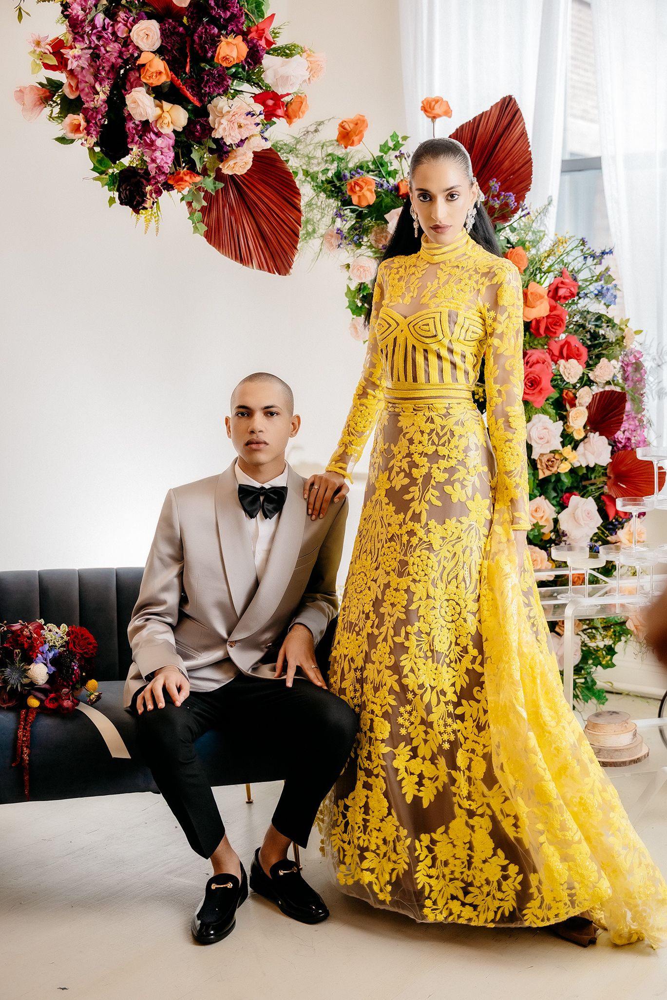 Formal portrait with yellow embellished gown against floral backdrop with burgundy accents.