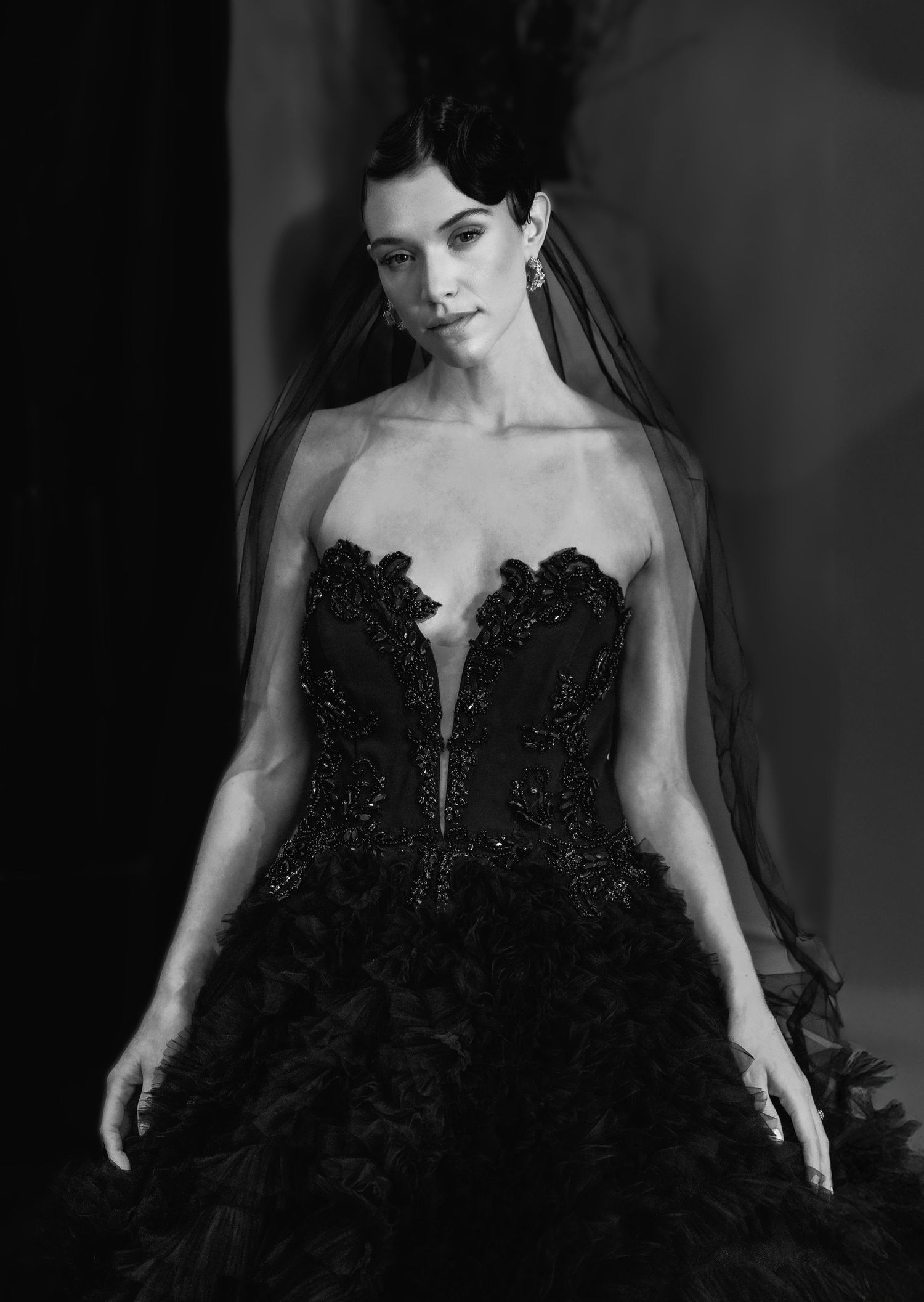 Black and white portrait of a dramatic black wedding gown with plunging neckline and beaded details.