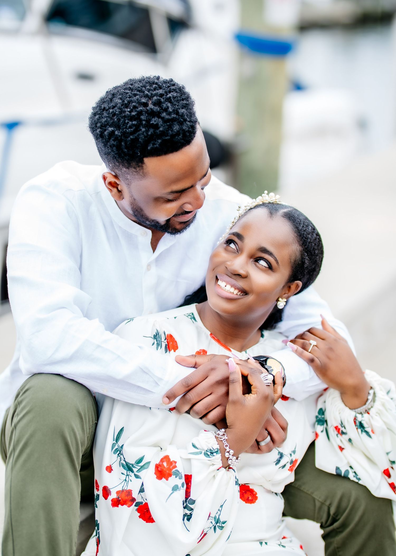 A couple shares a tender romantic moment as they embrace and smile while wearing coordinating white and olive green outfits.