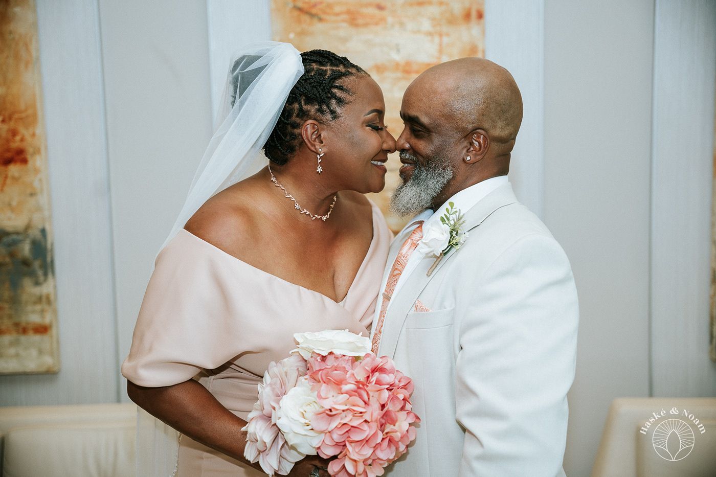 Intimate wedding portrait with pink bouquet and white formal attire.