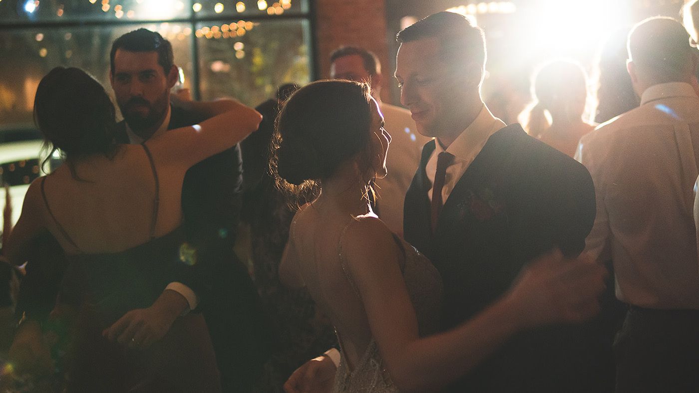 Guests dancing and celebrating at a dimly lit evening wedding reception.