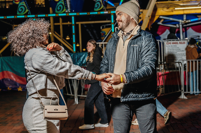 Two people dancing together at a colorful carnival at night.