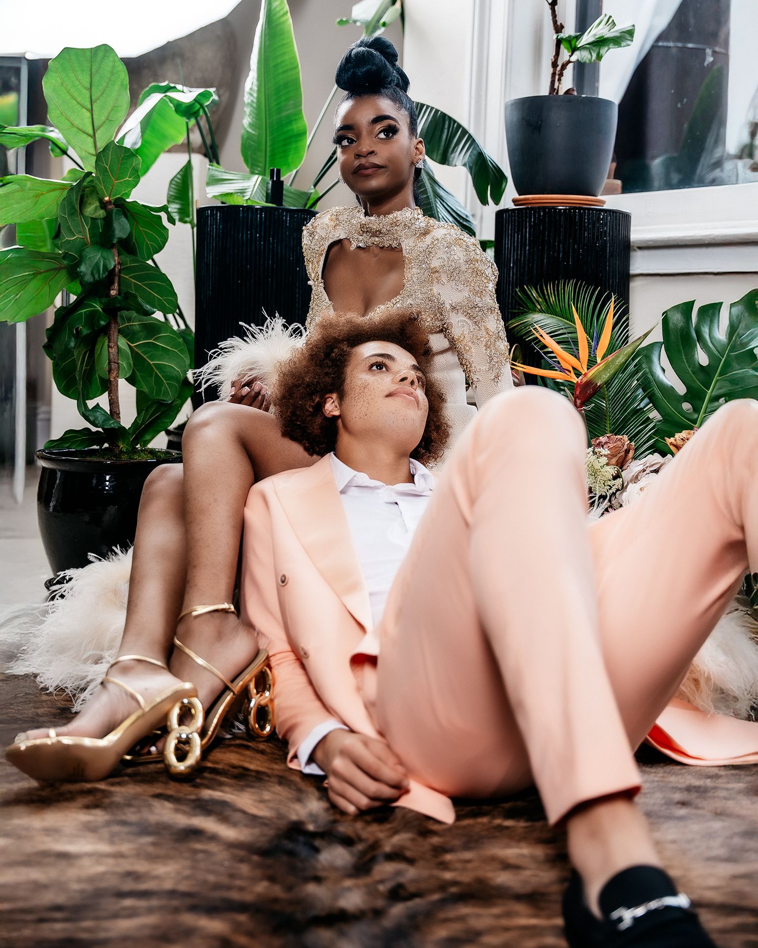 Stylish fashion editorial featuring luxurious lace and feather details among tropical plants.
