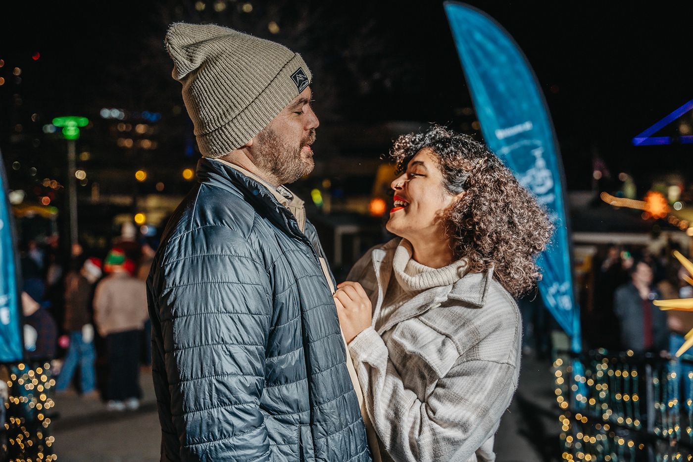 Happy couple sharing a tender moment at an outdoor festival with lights and decorations.