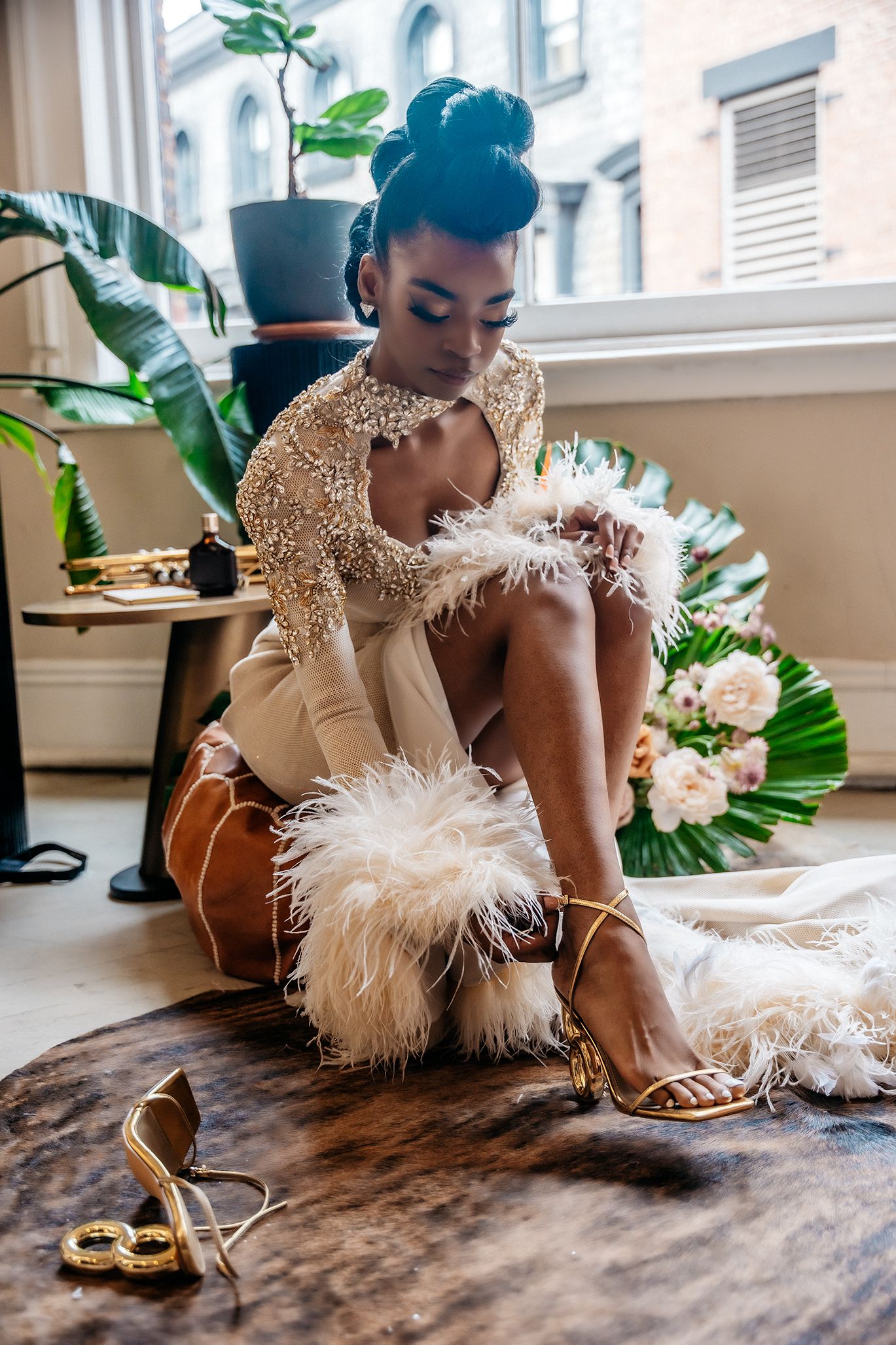 Fashion photo with beaded dress and feather details against urban window backdrop.