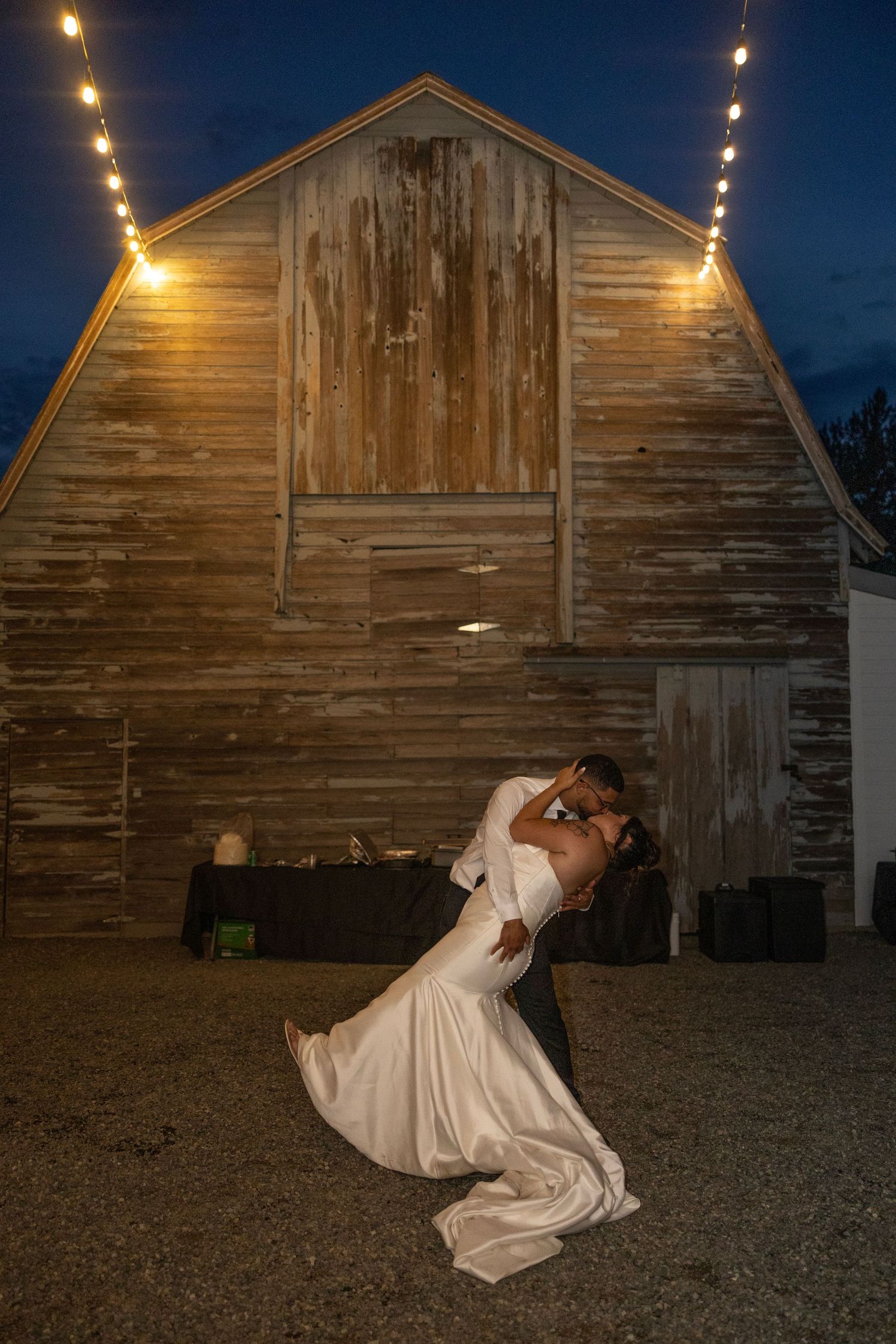 A sequence of photos showing a figure in a white dress being dramatically dipped in front of a rustic barn at dusk.