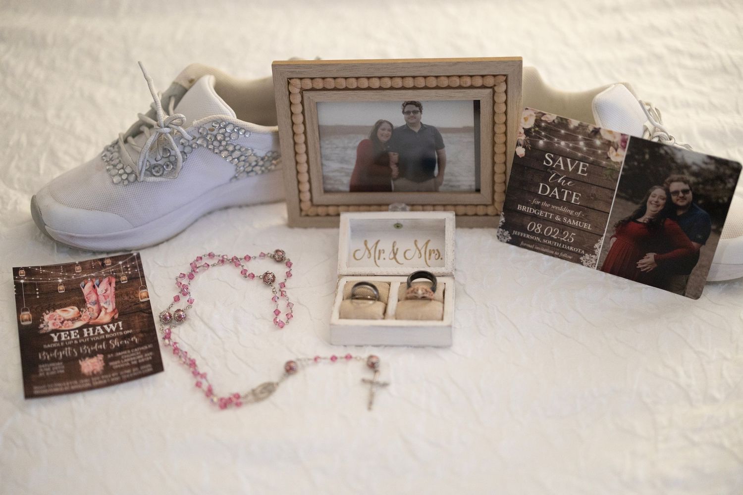 A collection of framed photos, jewelry, and personal mementos arranged on a white textured surface.