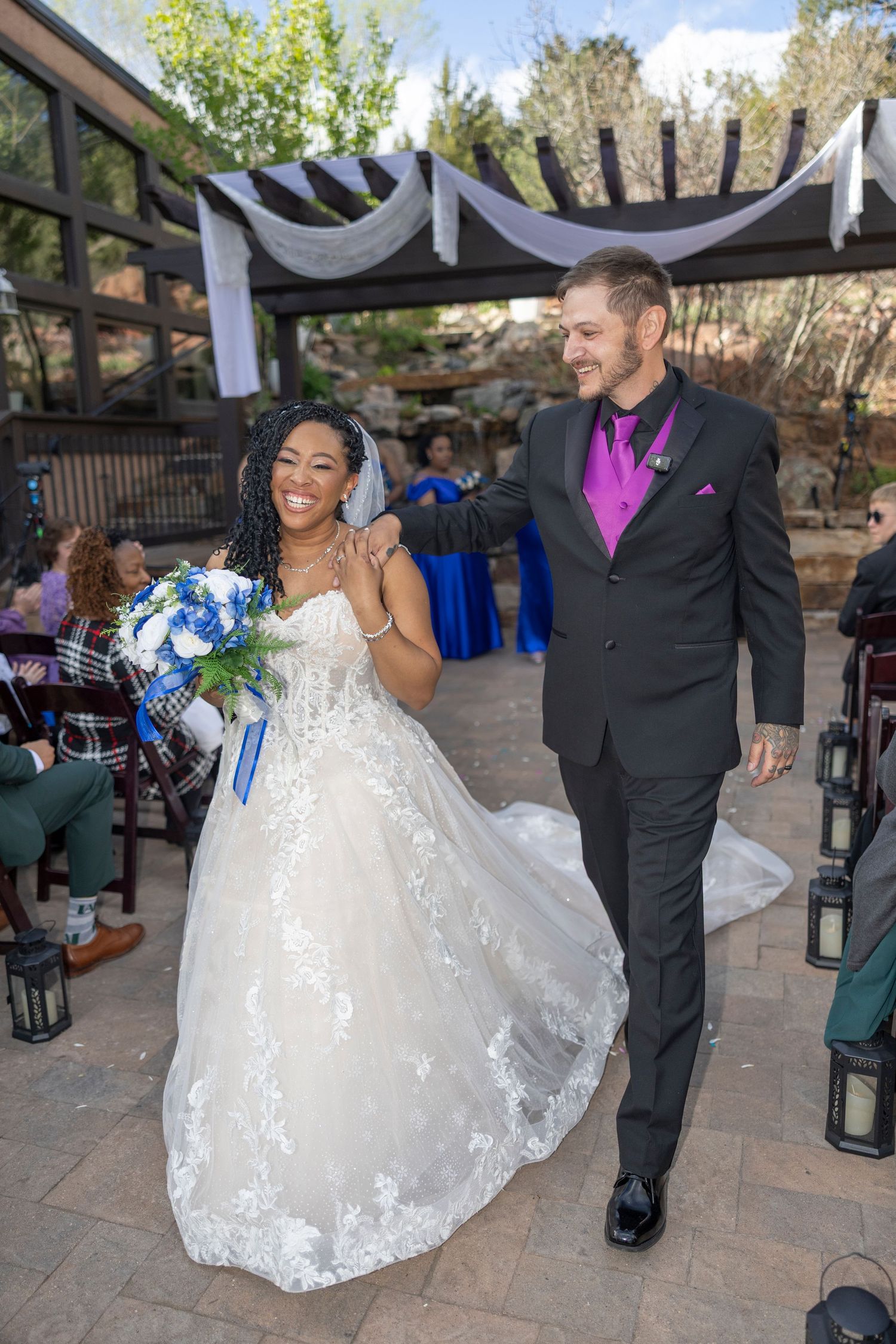 Wedding celebration on a stone patio with guests dancing and celebrating in formal attire.