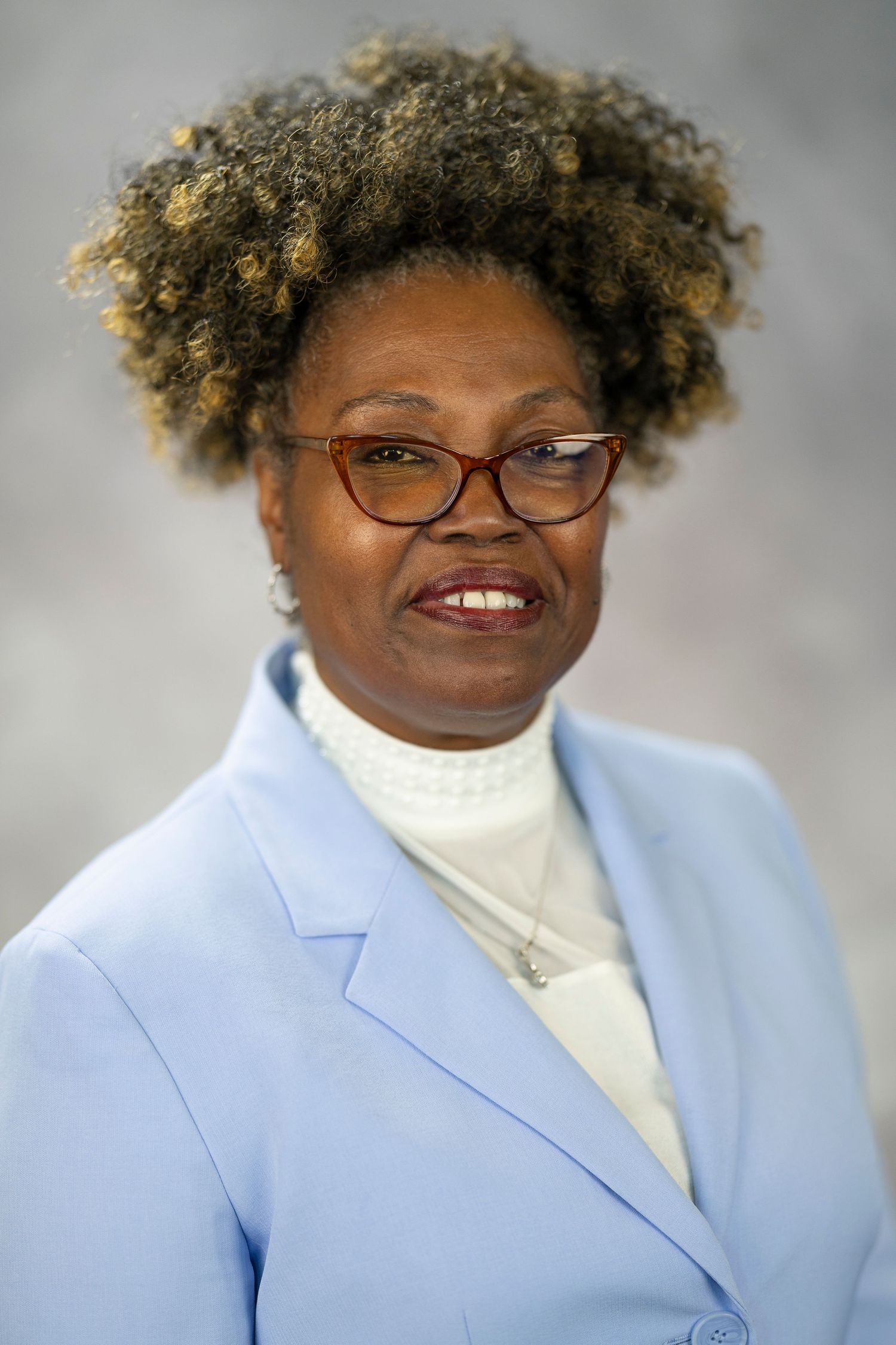 Professional headshot series showing different angles and expressions wearing a light blue blazer and white turtleneck.