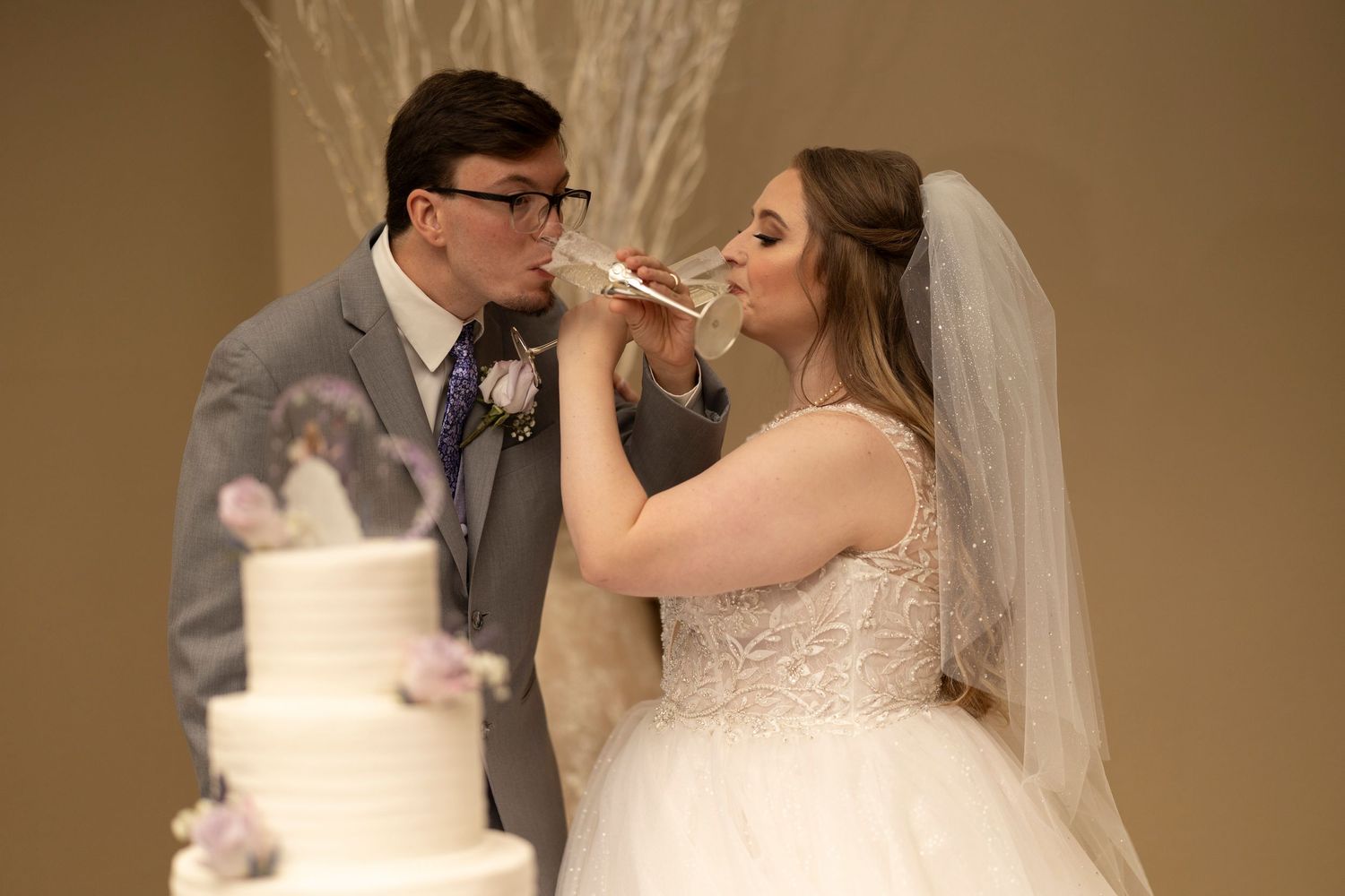 Newlyweds share a playful moment while cutting their white wedding cake.