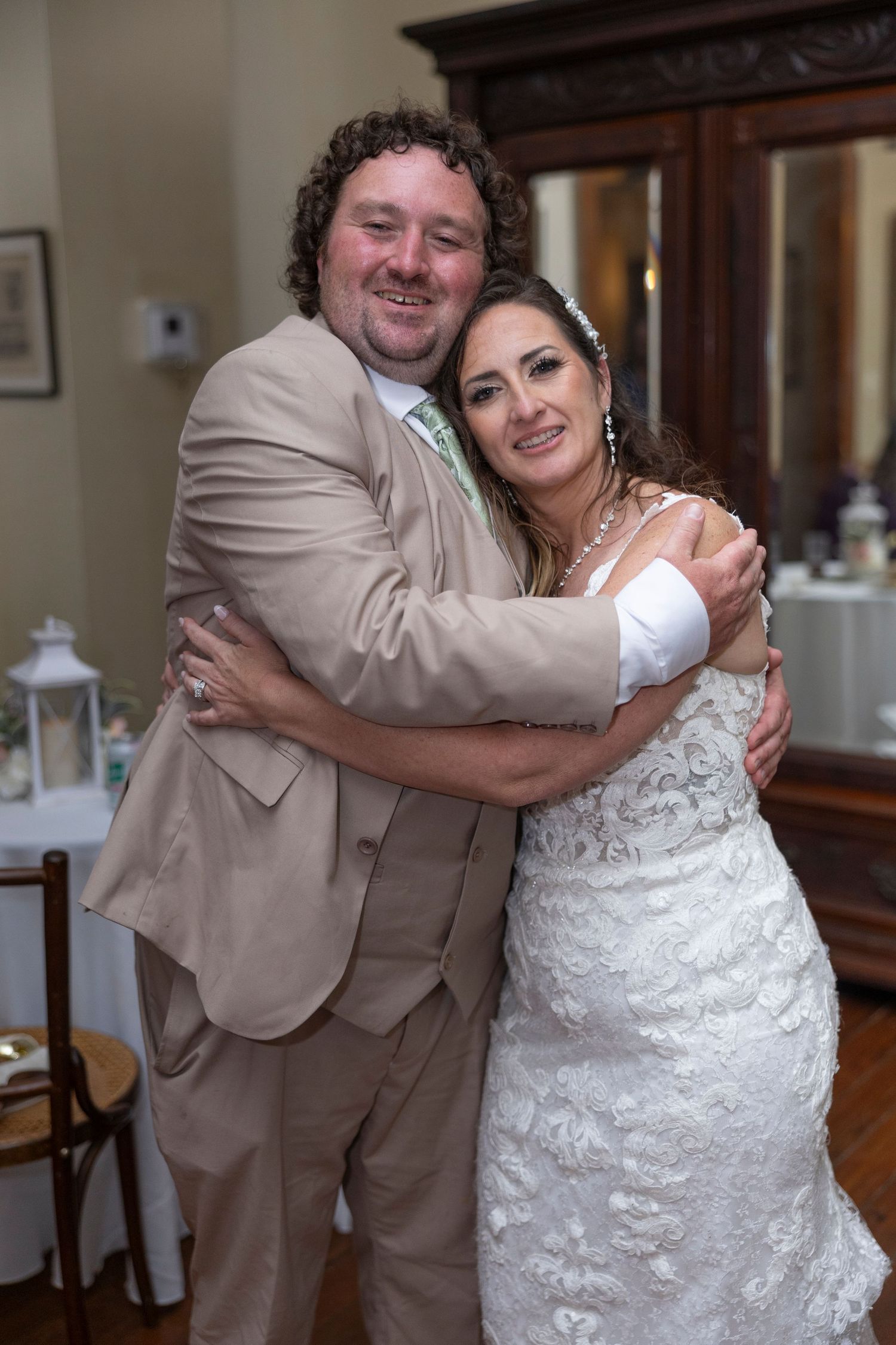 A couple shares a joyful embrace during their wedding celebration in an indoor venue.
