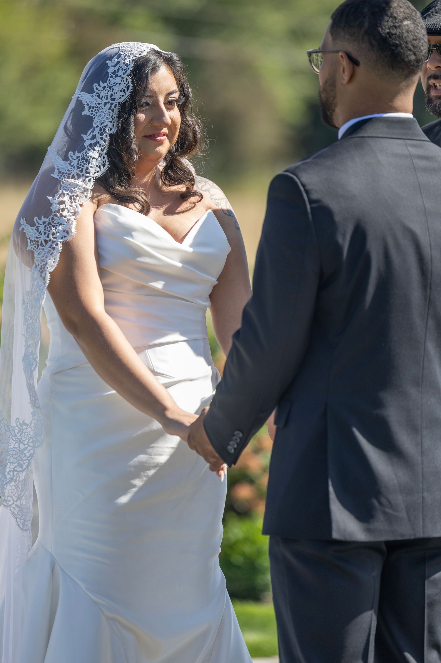 A bride and groom share a tender moment during their outdoor wedding photoshoot in a garden setting.