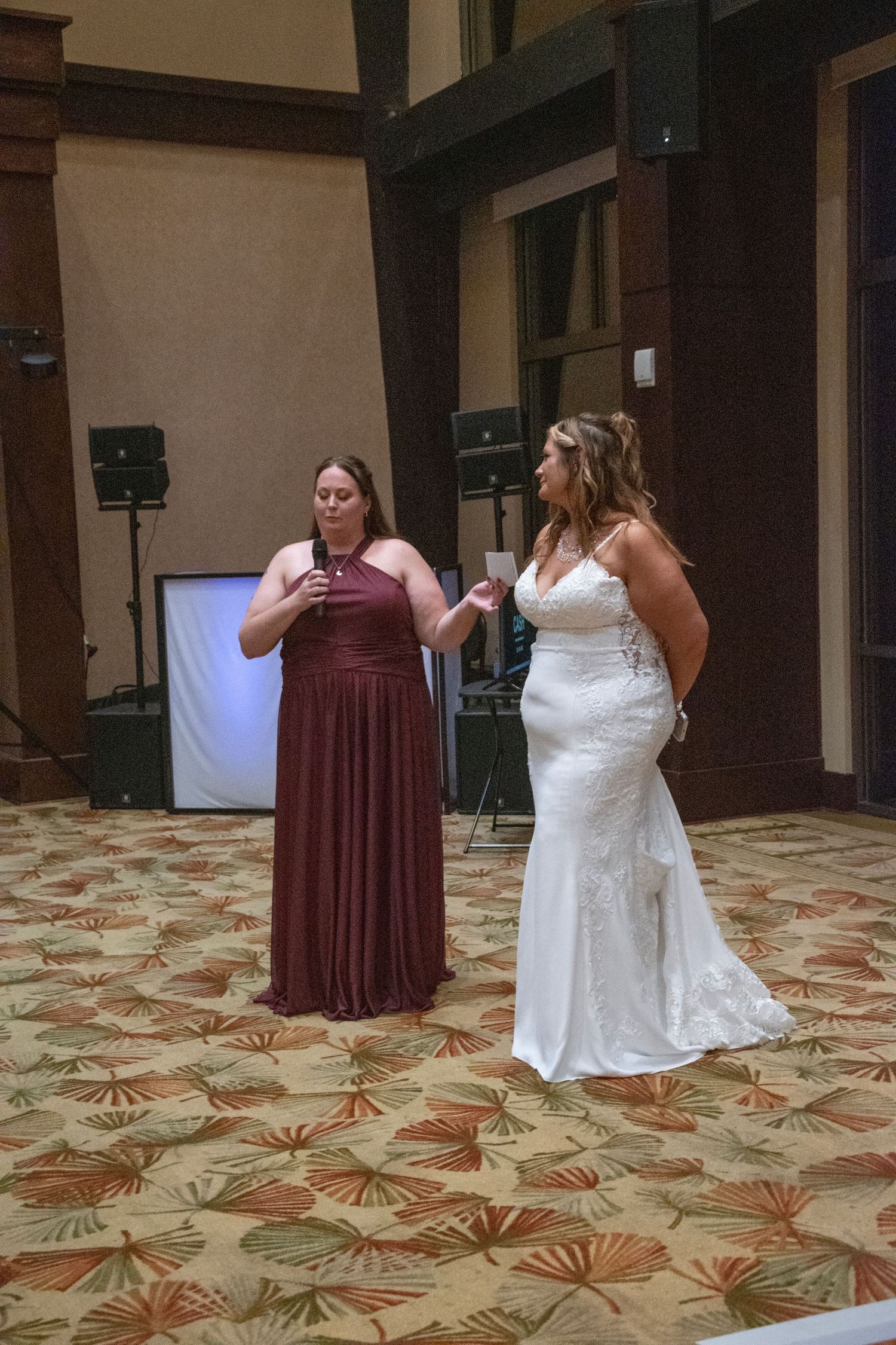Two people in formal attire dance together on a patterned ballroom floor during a celebration.