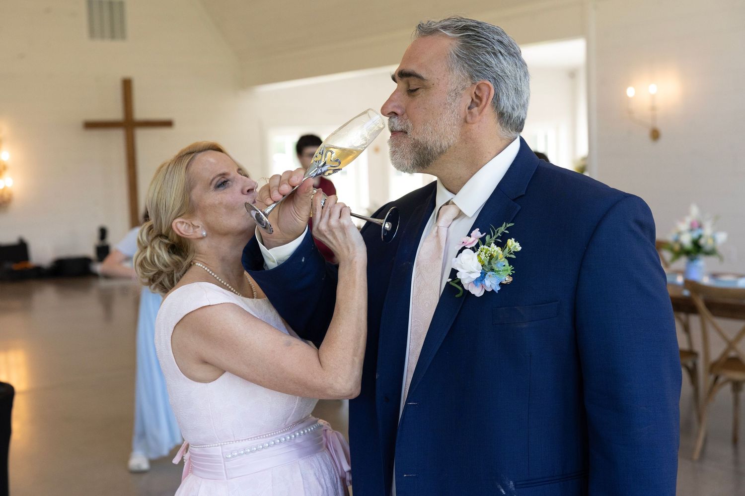 Bride and groom sharing a champagne toast at their wedding reception in a church venue.