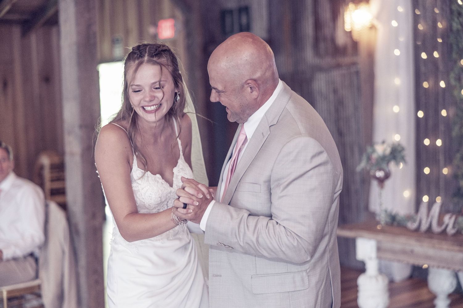 A bride and her father share an emotional dance together at an elegant wedding reception.